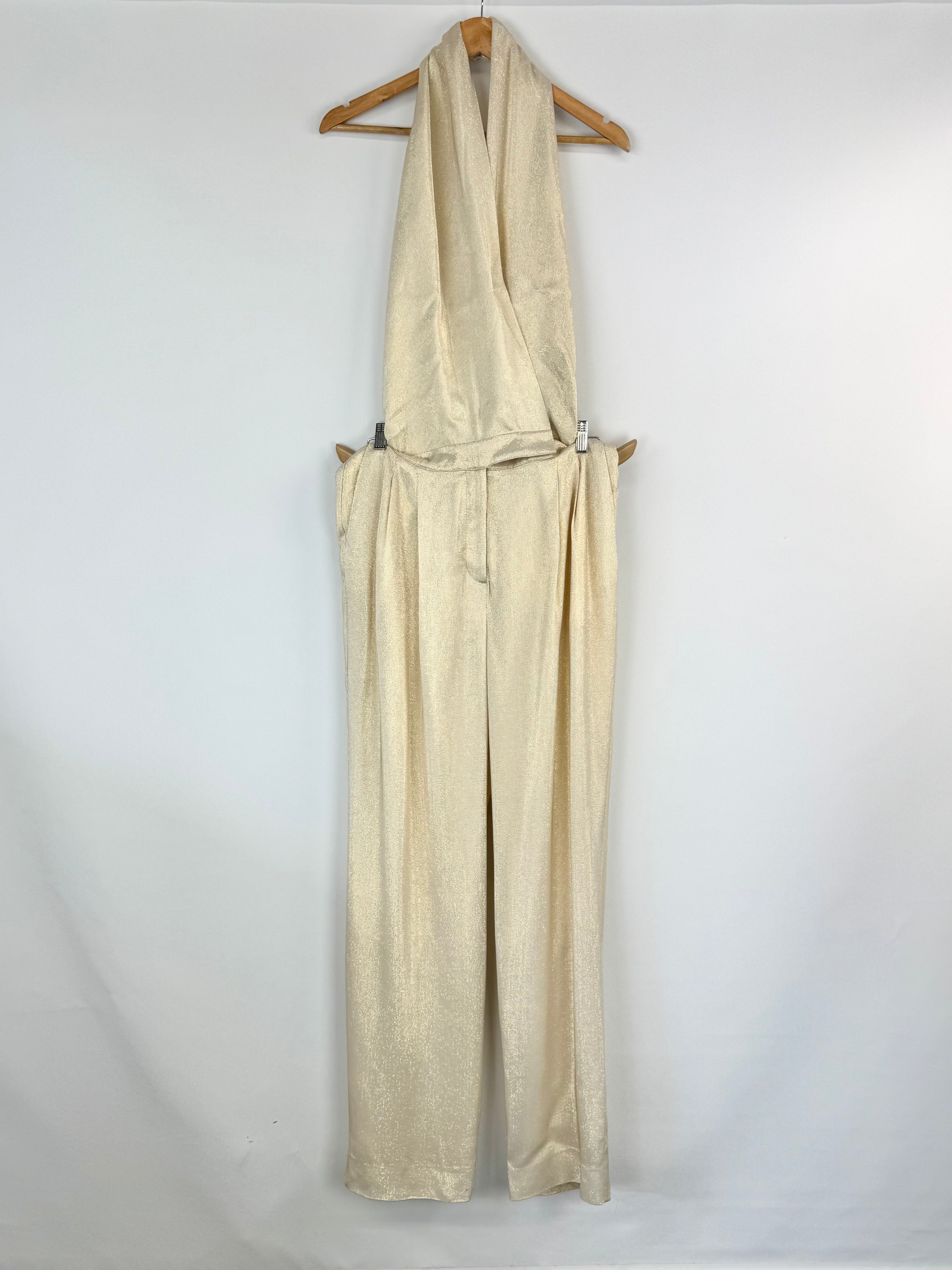 Gold jumpsuit on a wooden hanger against a white background