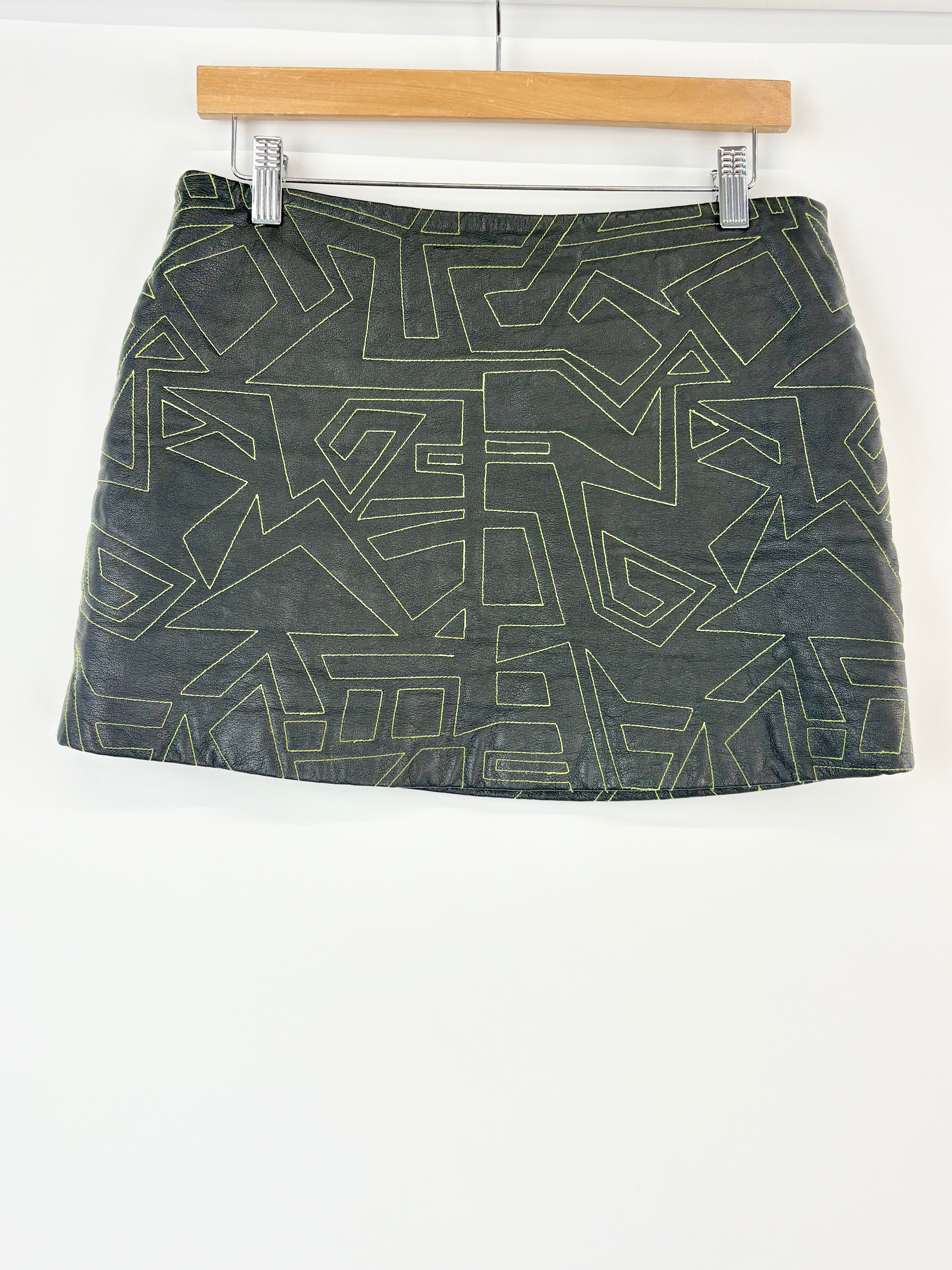 Black leather skirt with geometric pattern on a hanger against a white background