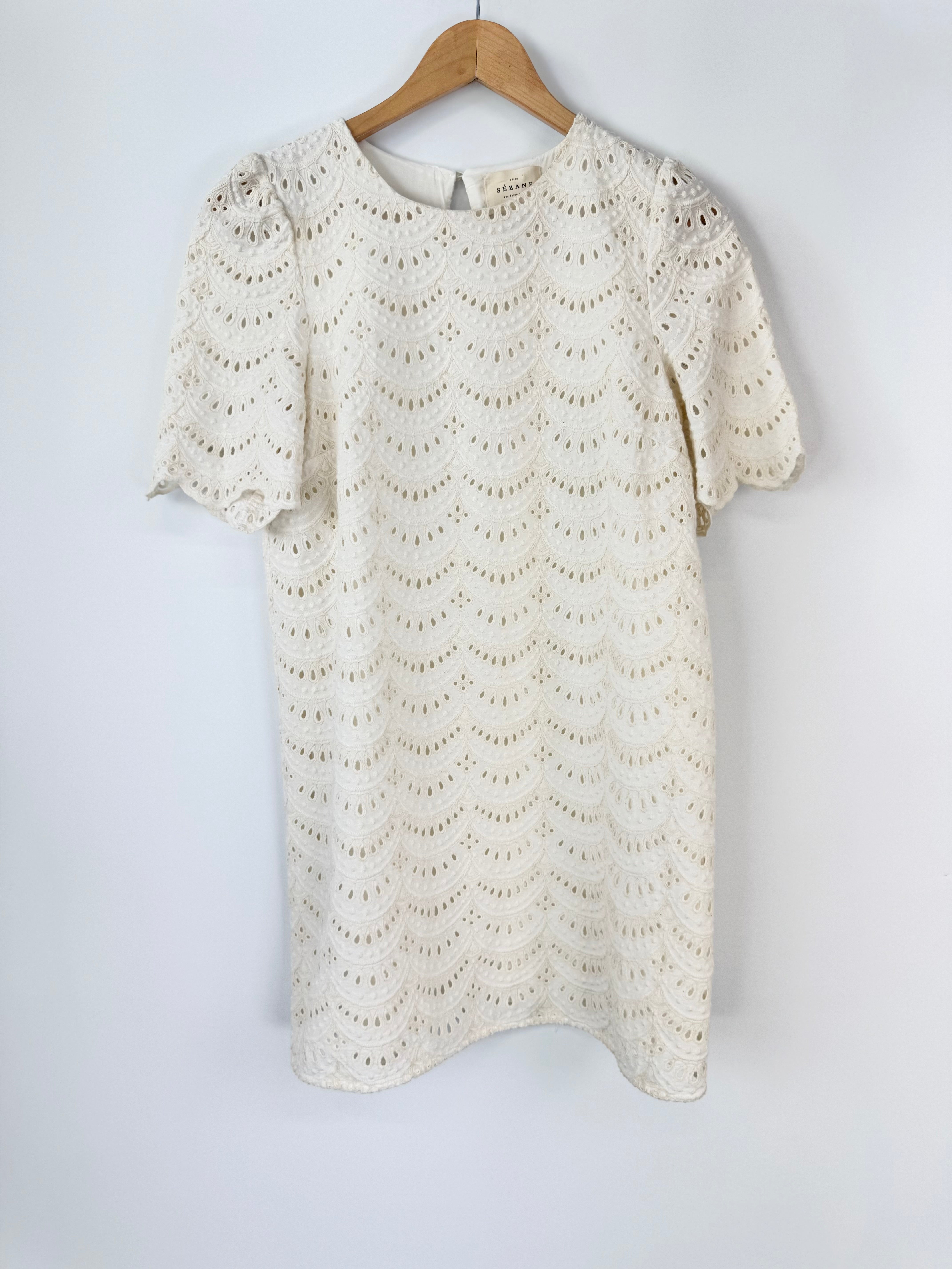 White lace dress on a wooden hanger against a white background