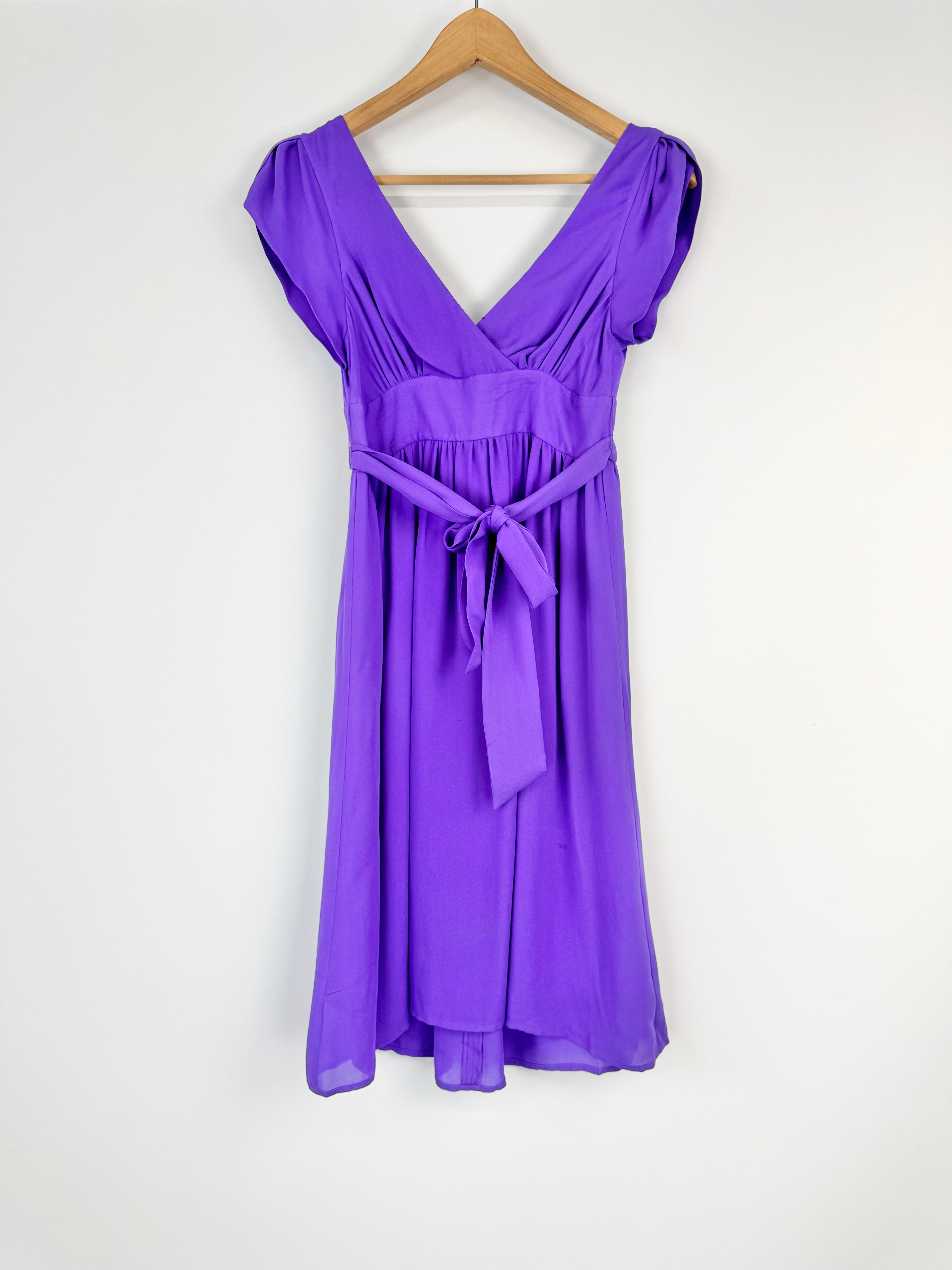 Purple dress on a hanger against a white background