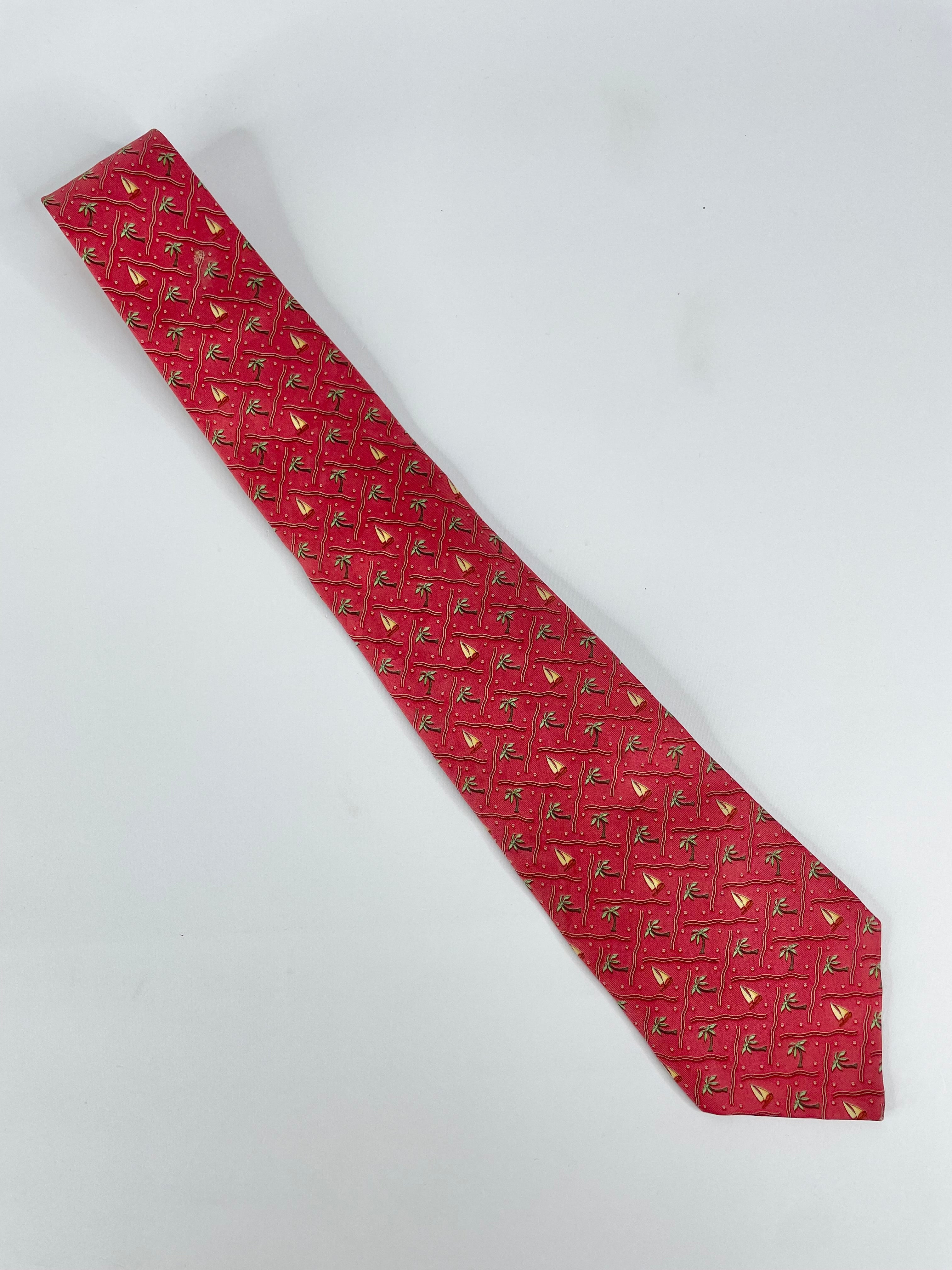 A red silk tie with a pattern of palm trees and sailing yachts.