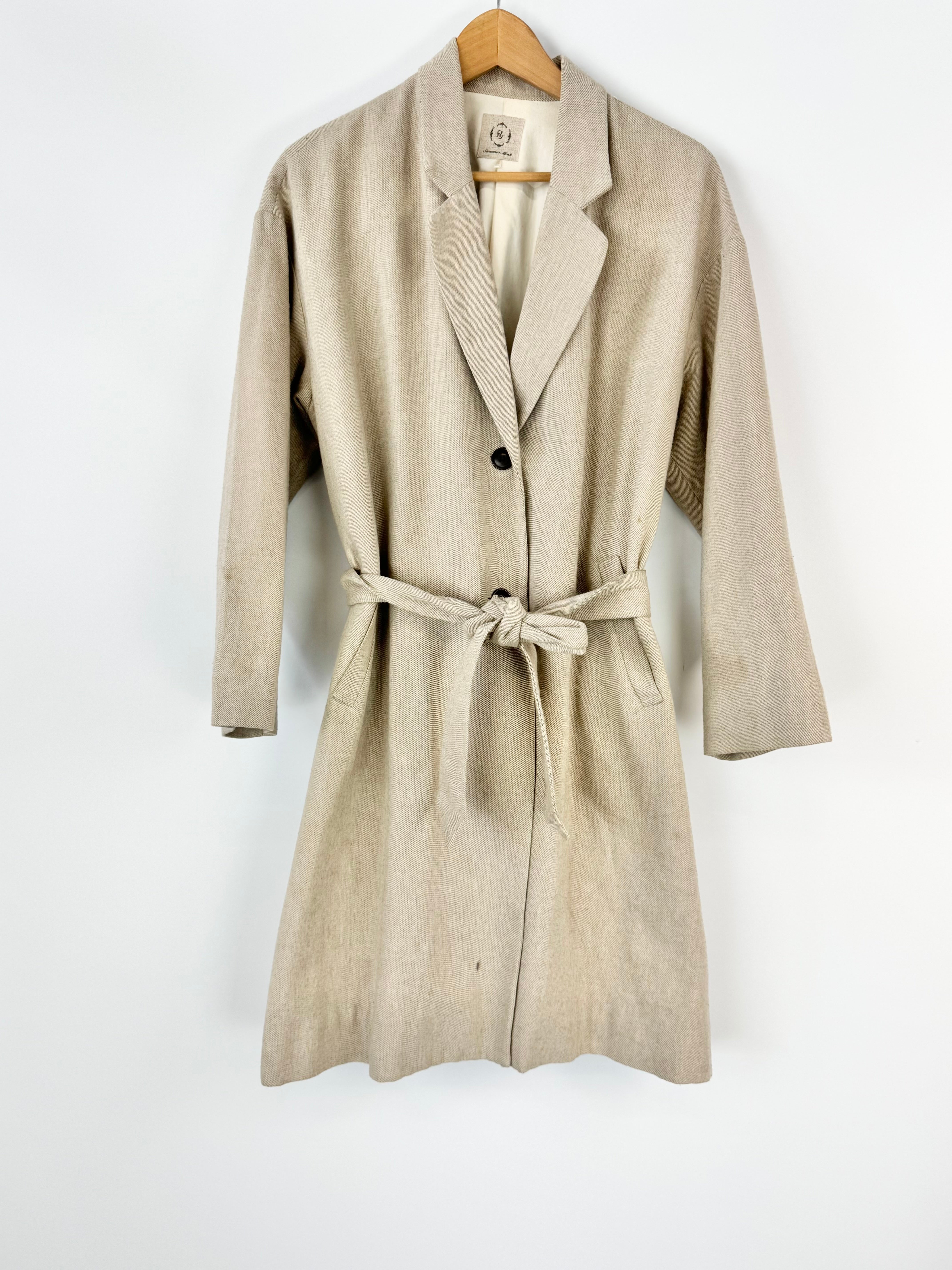 Beige trench coat on a hanger against a white background