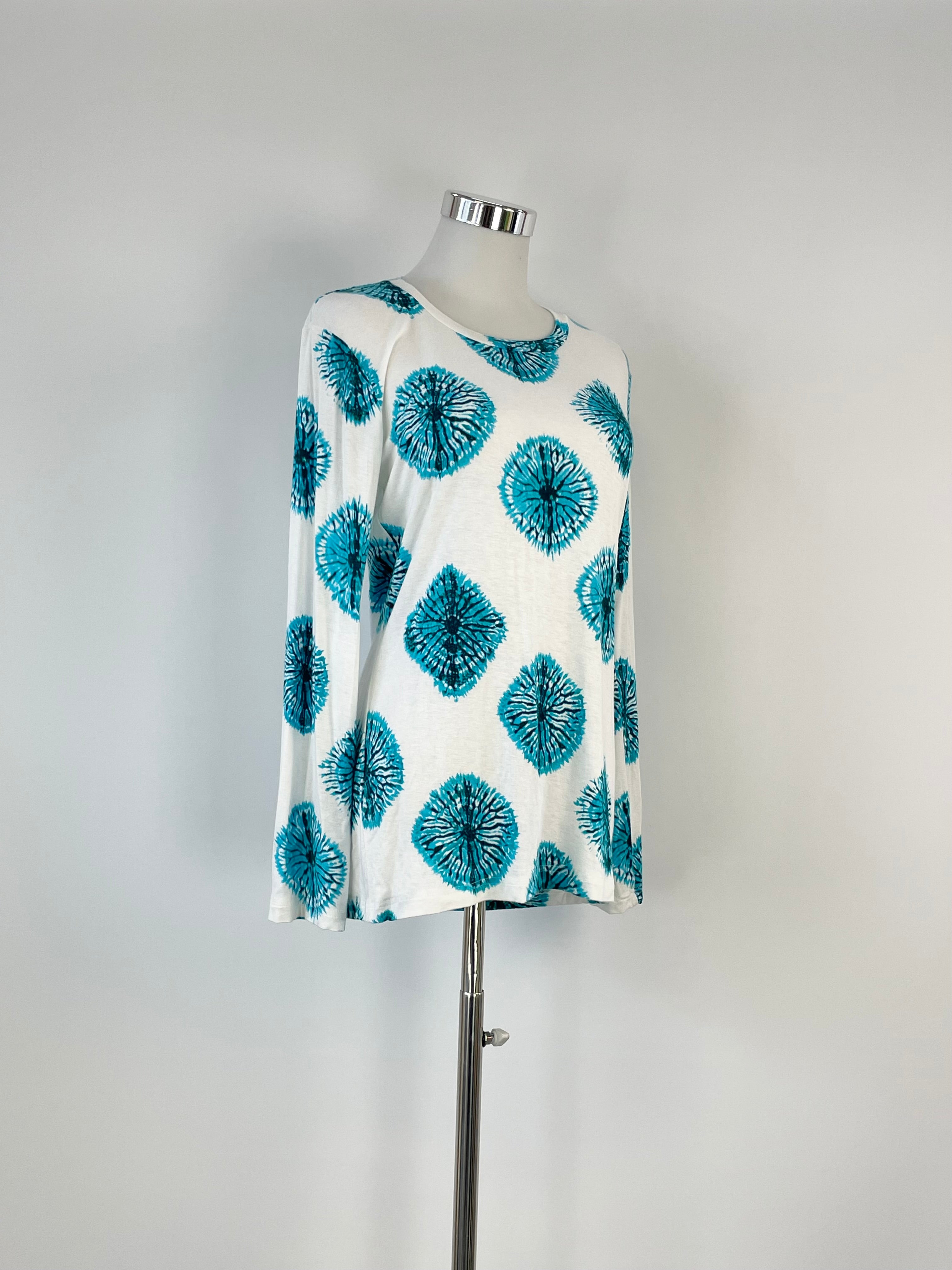 A white and teal print top displayed on a mannequin against a plain background.