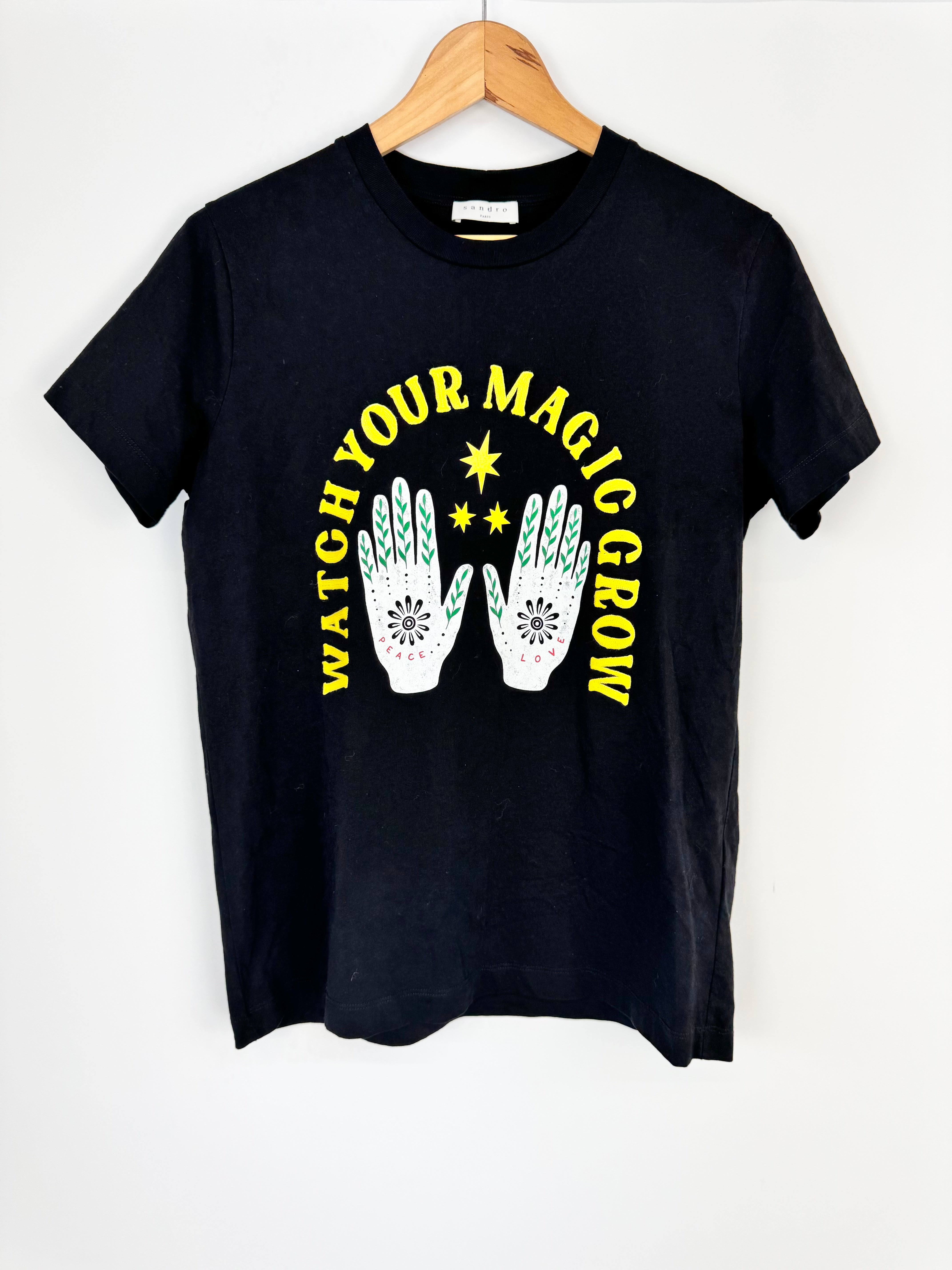 Black t-shirt with 'Watch Your Magic Grow' text and hand designs on a white background
