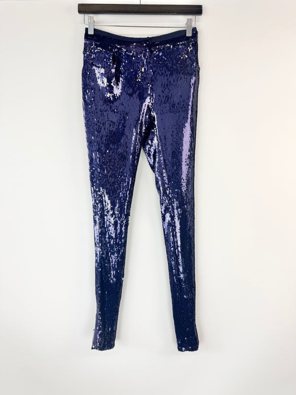 Navy blue sequin leggings on a hanger against a white background