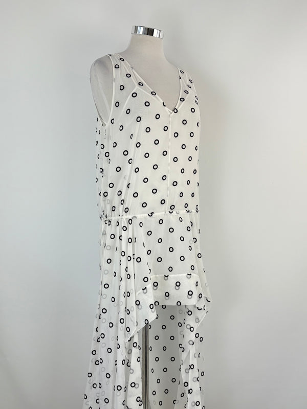 White dress with black polka dots on a mannequin against a gray background