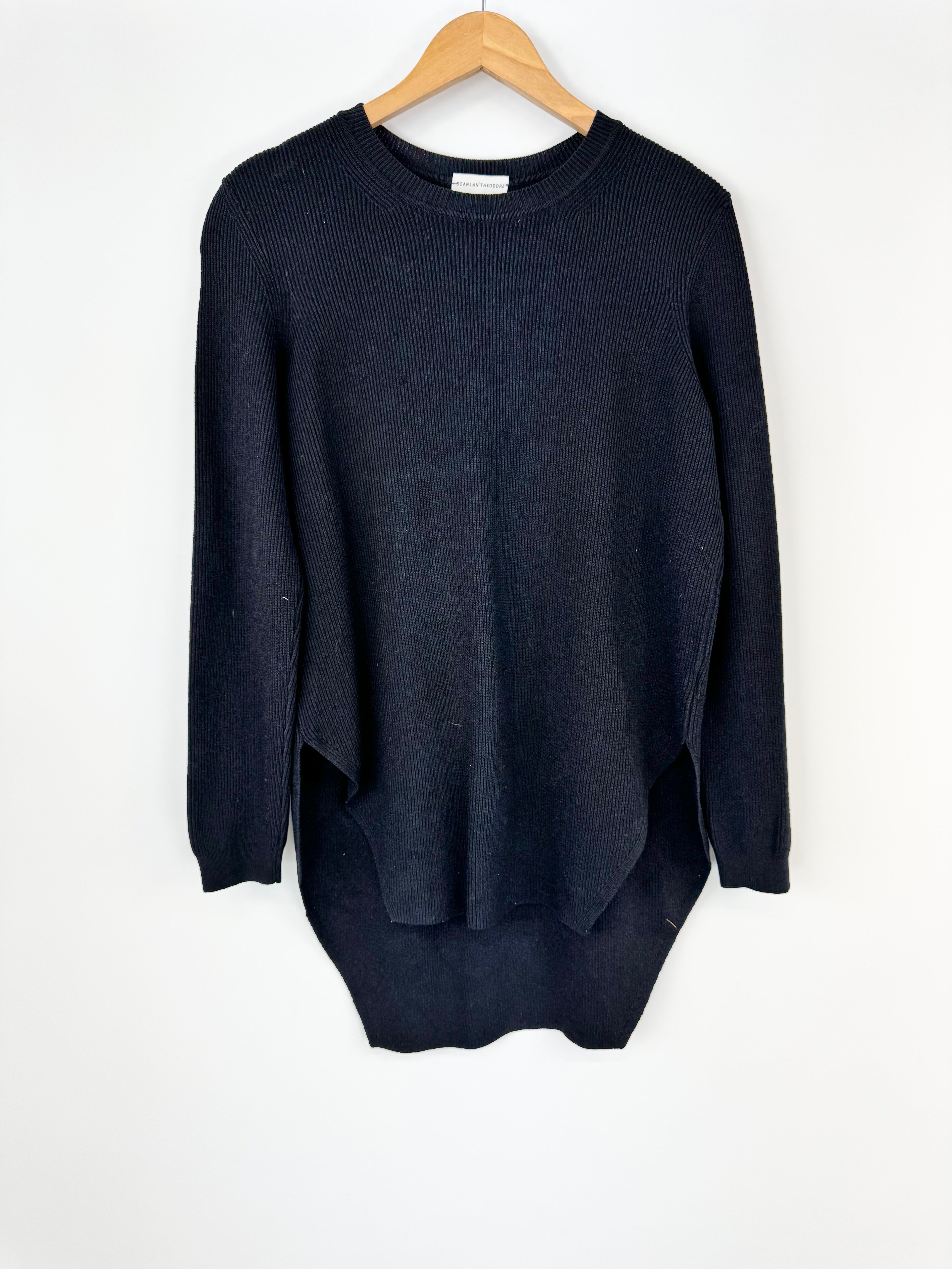Black blue sweater on a wooden hanger against a white background