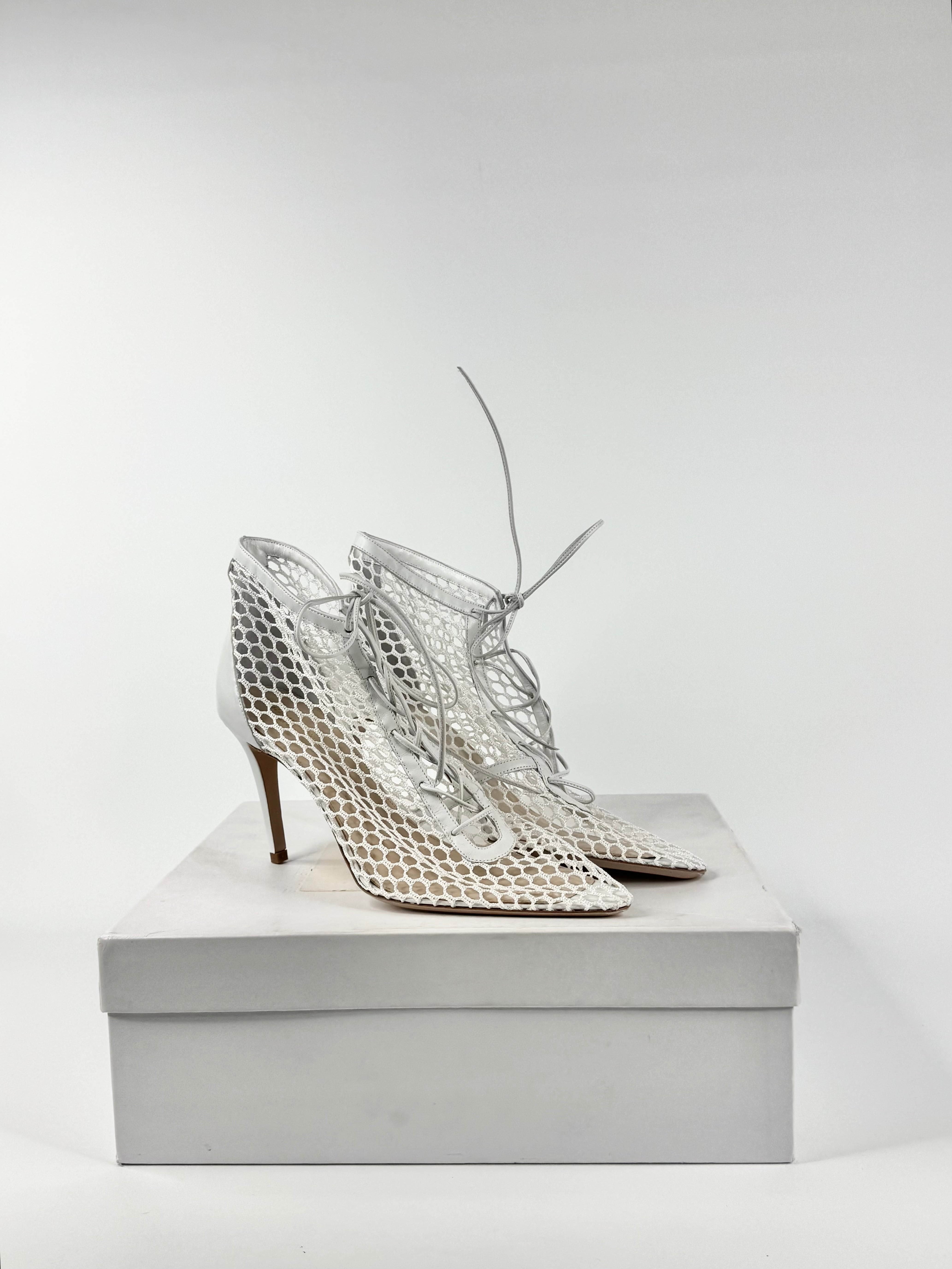 Pair of silver high-heeled shoes on a white box against a light gray background