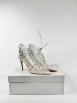 Pair of silver high-heeled shoes on a white box against a light gray background