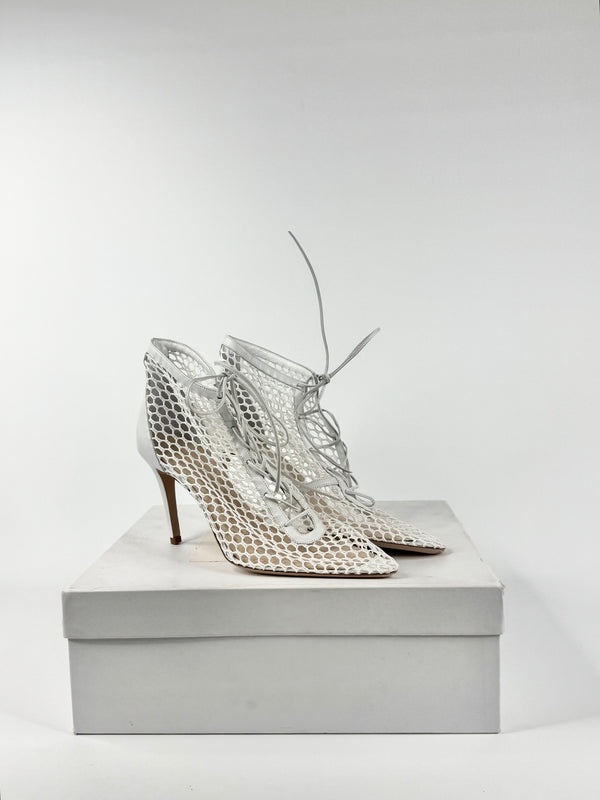 Pair of silver high-heeled shoes on a white box against a light gray background