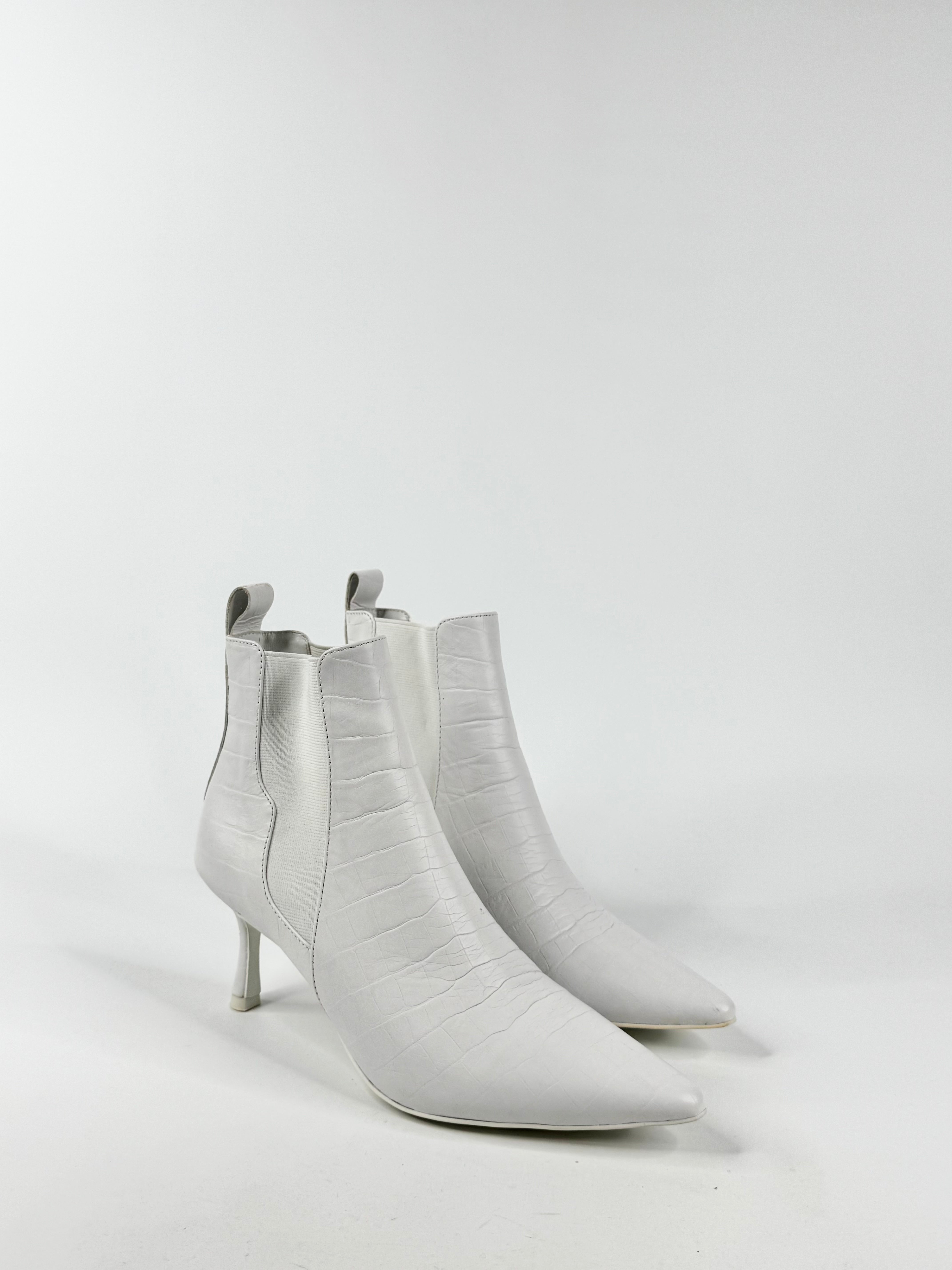 Pair of white ankle boots on a light gray background