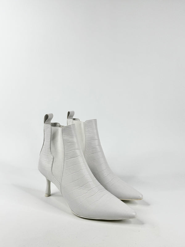 Pair of white ankle boots on a light gray background