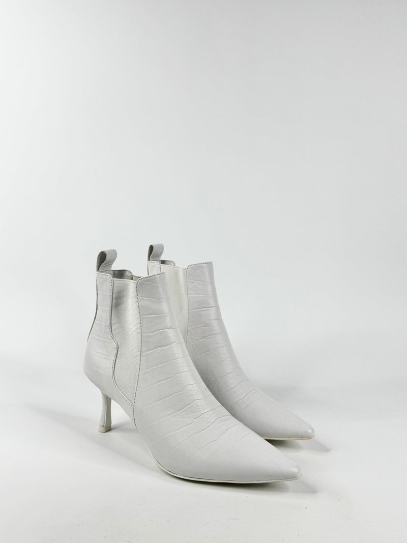 Pair of white ankle boots on a light gray background