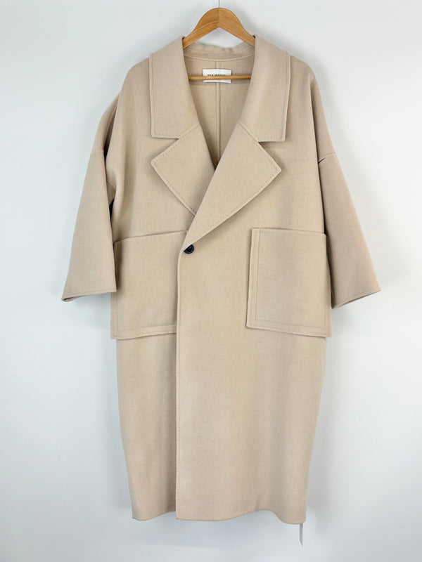 Silk Maison ivory coat on a hanger against a white background