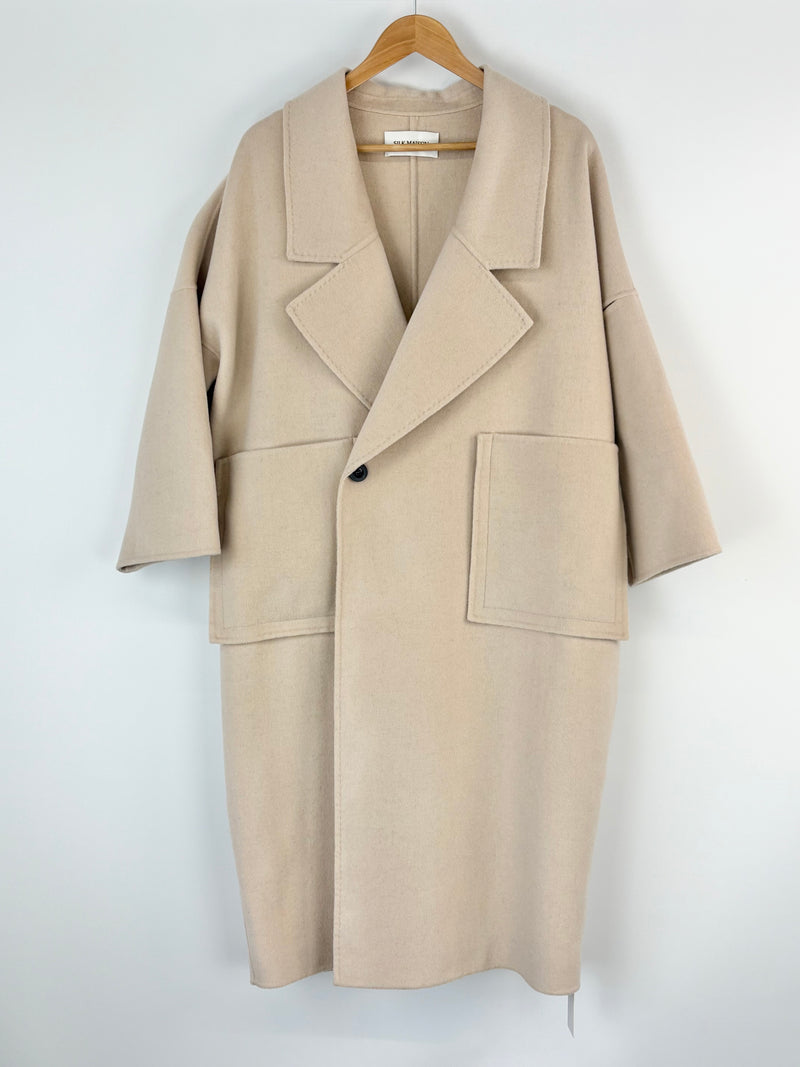 Silk Maison ivory coat on a hanger against a white background