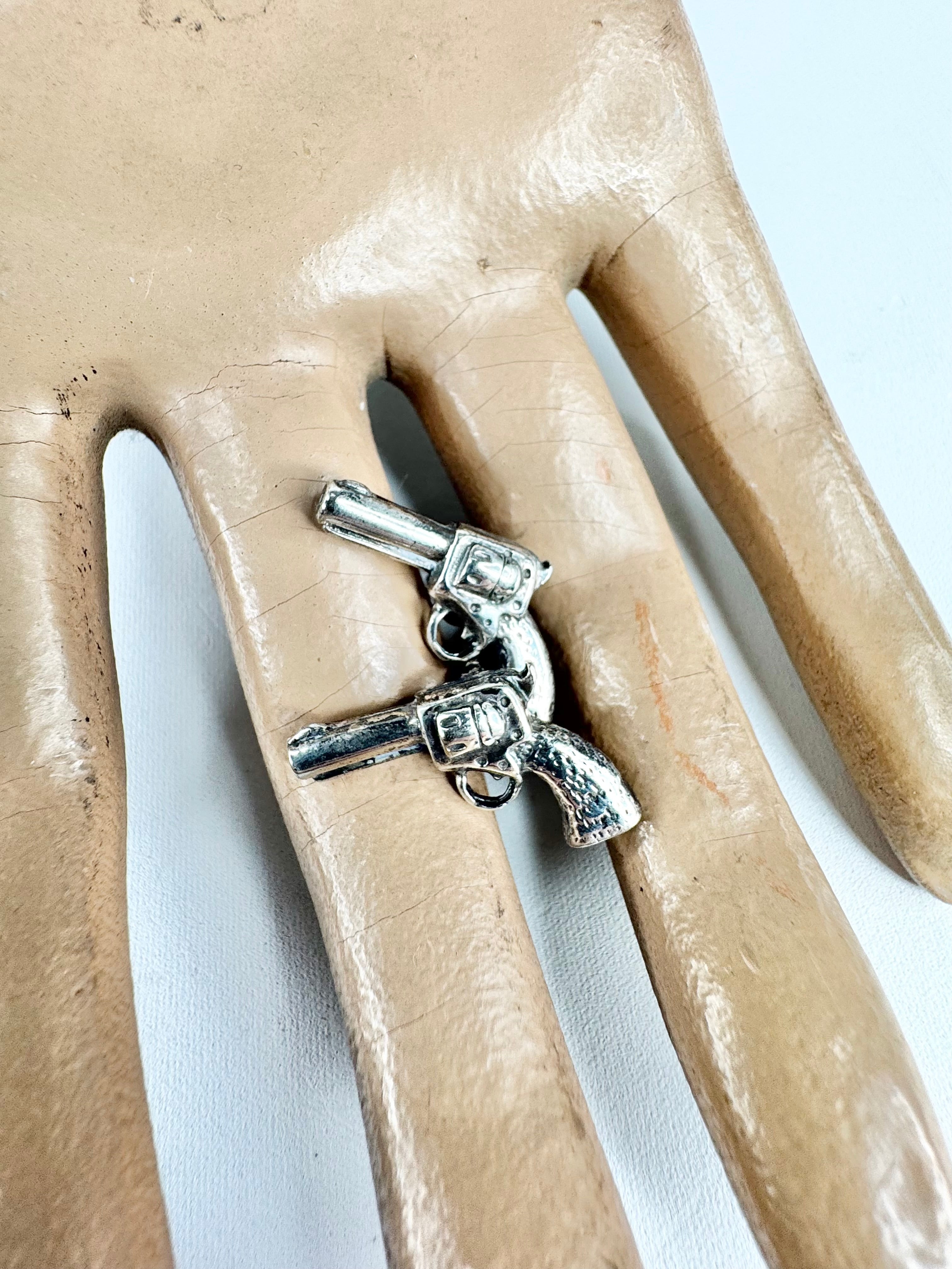 Two Silver revolver cufflinks on a beige mannequin hand
