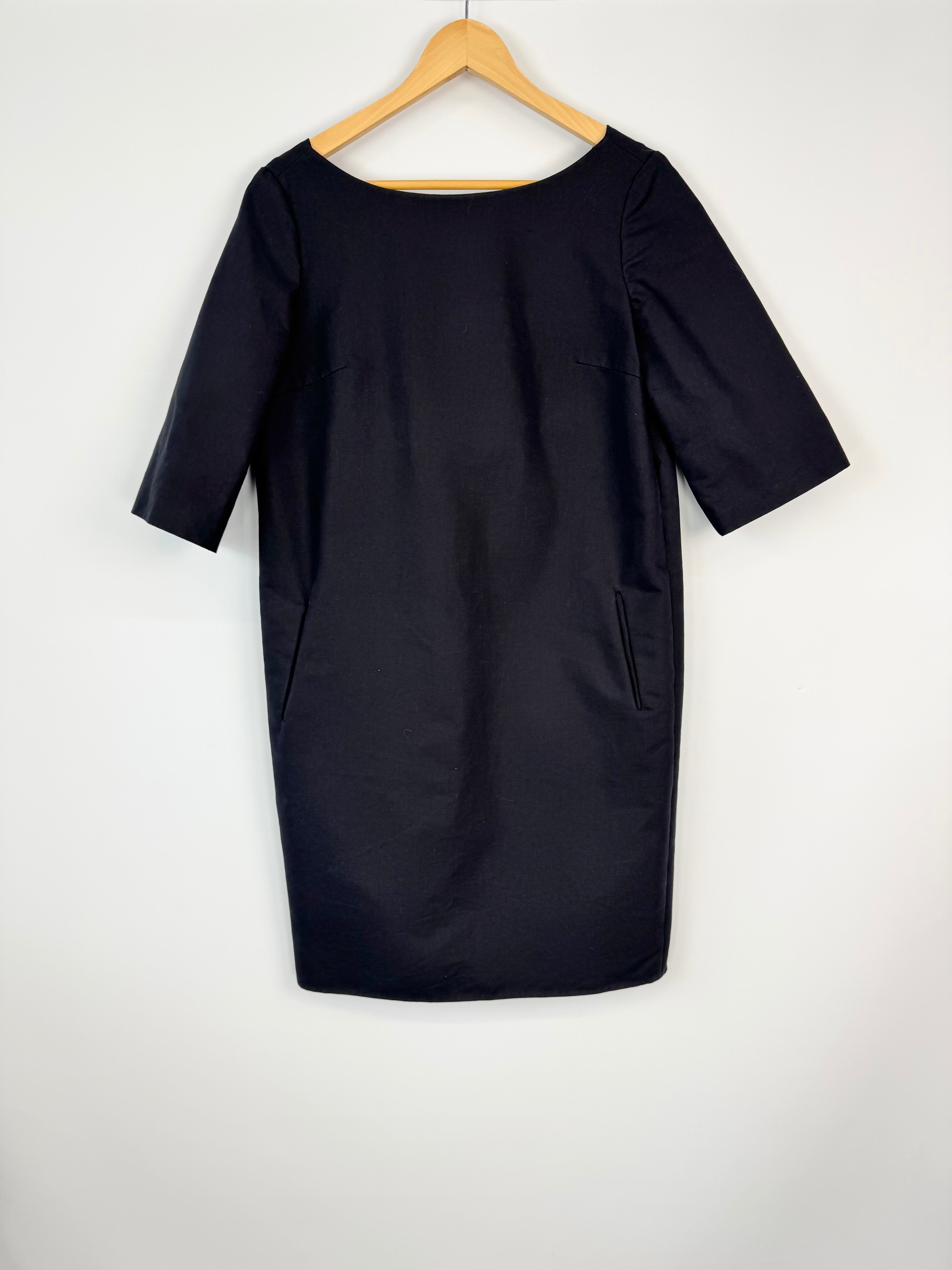 Black dress on a wooden hanger against a white background