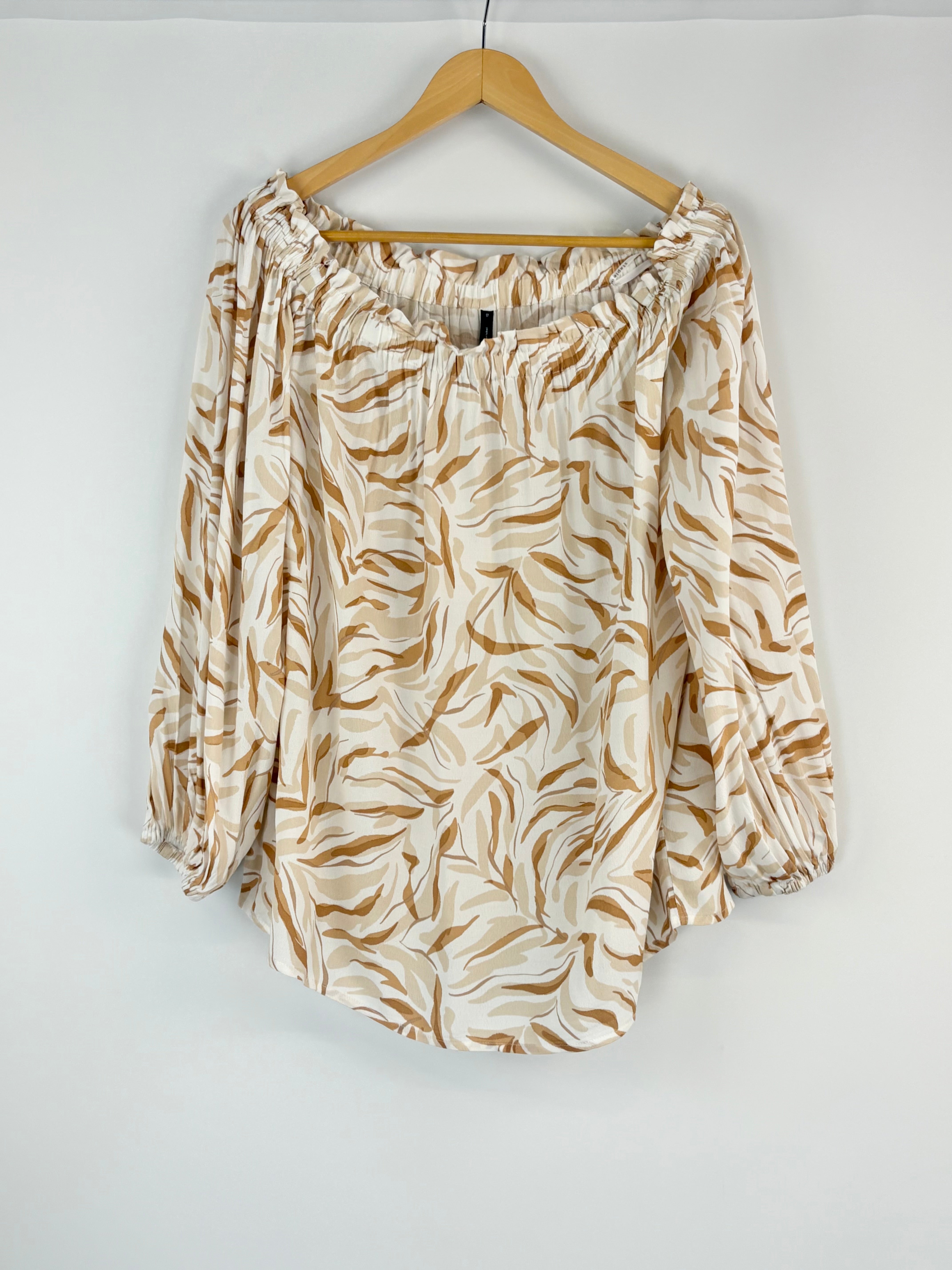 Beige and brown patterned blouse on a hanger against a white background
