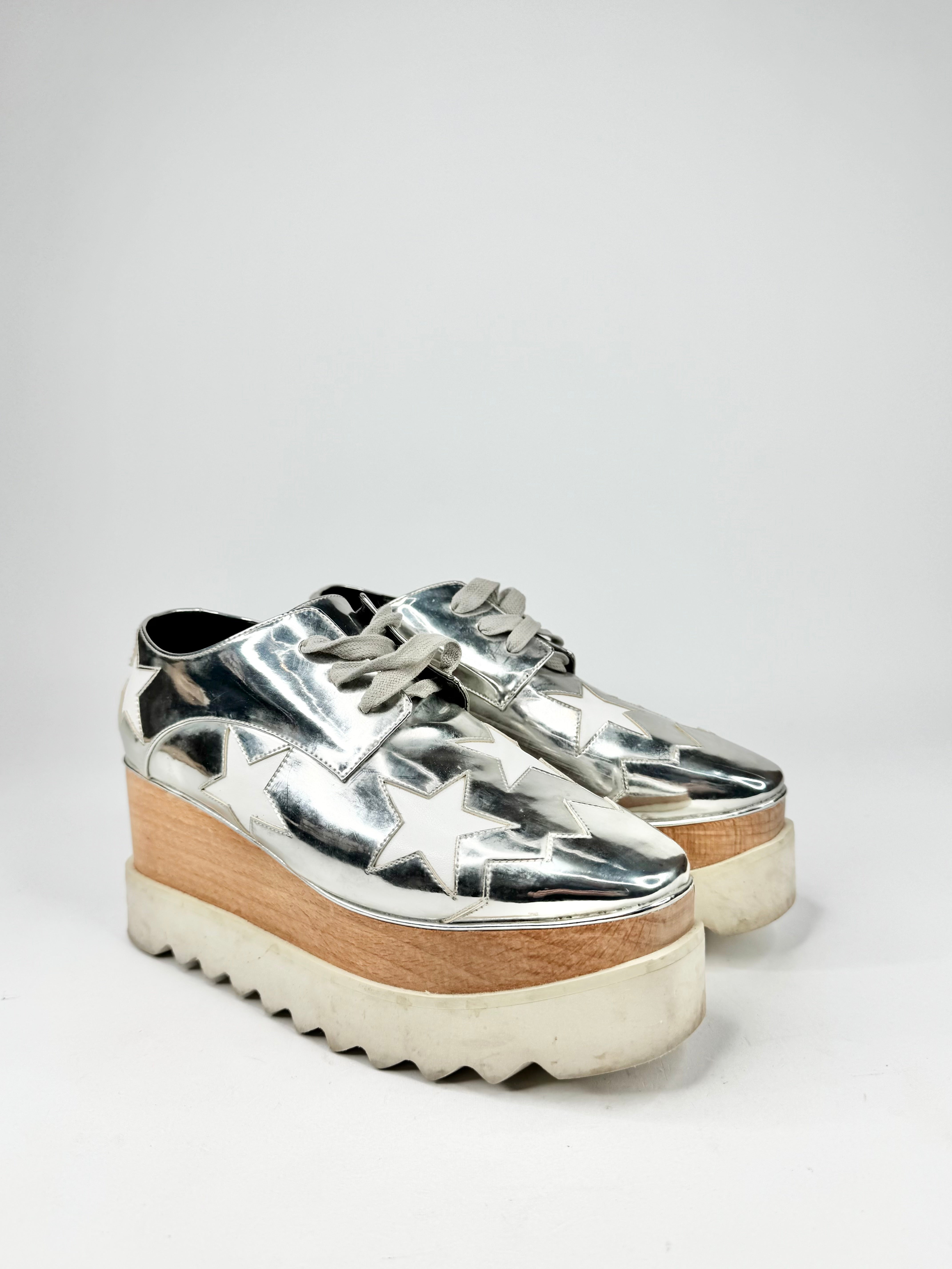 Silver platform shoes with wooden sole on a white background