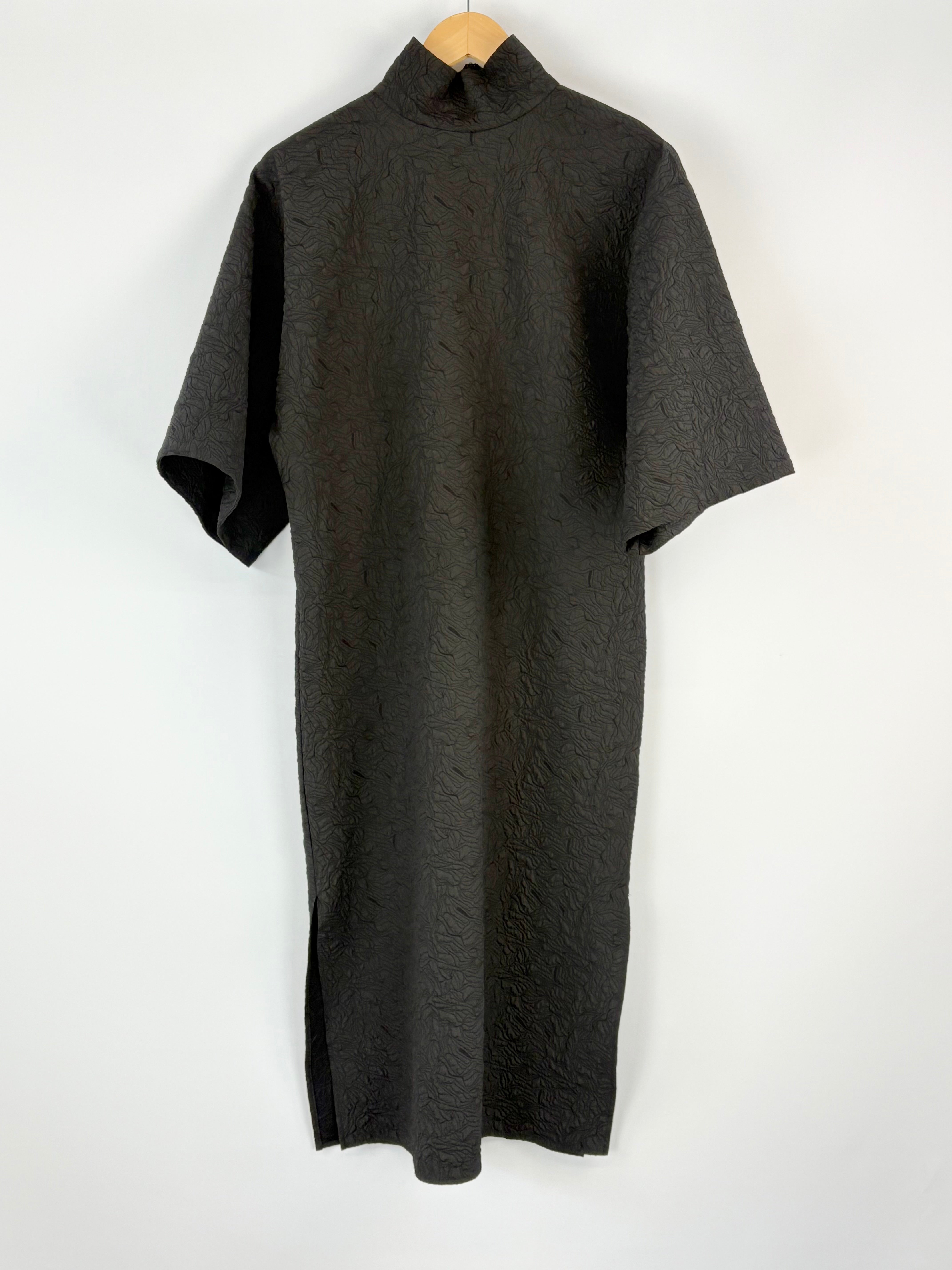 Black dress on a wooden hanger against a white background