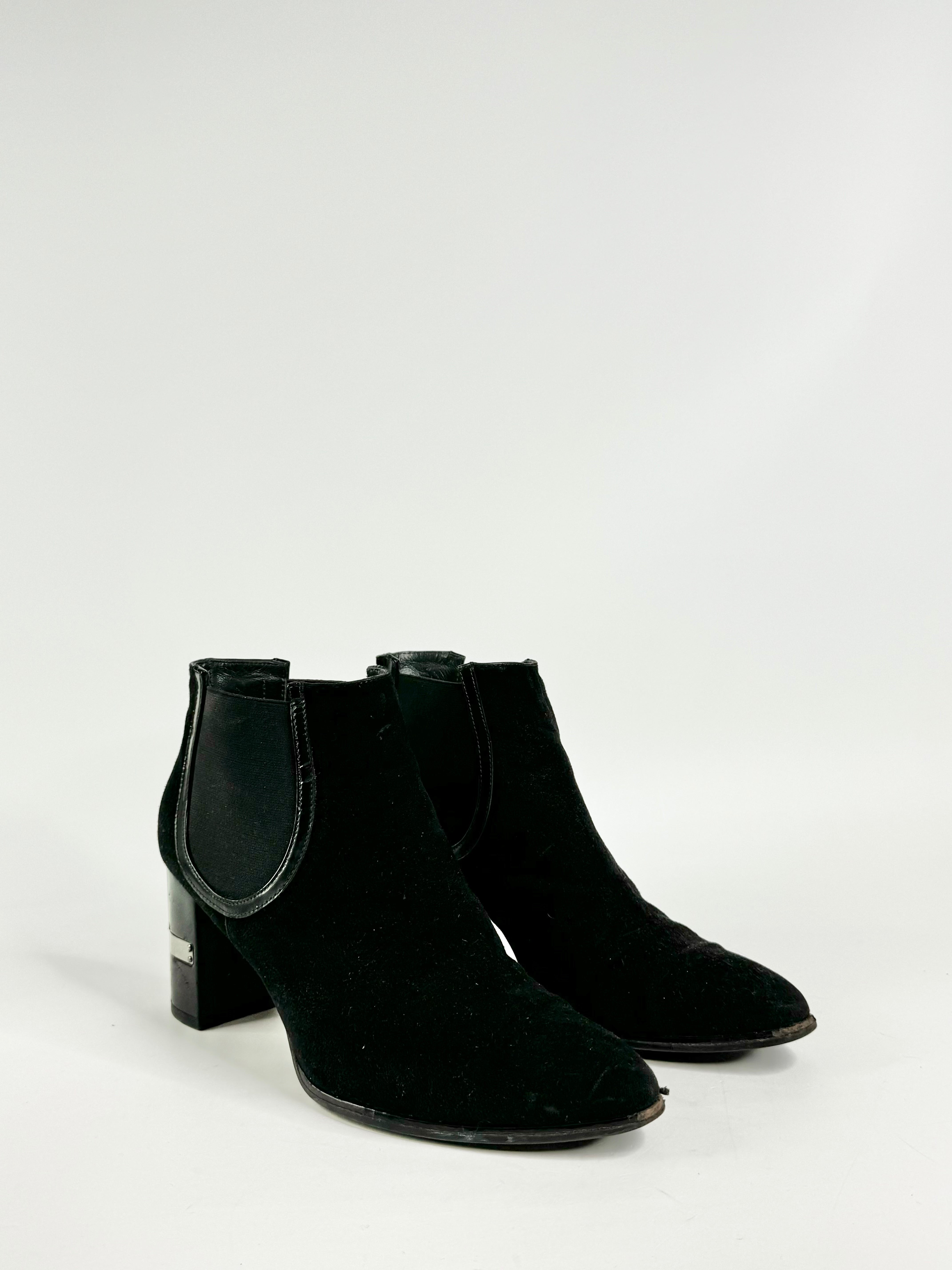 A pair of black suede Stuart Weitzman ankle boots with a small block heel and elastic panels, displayed against a white background.