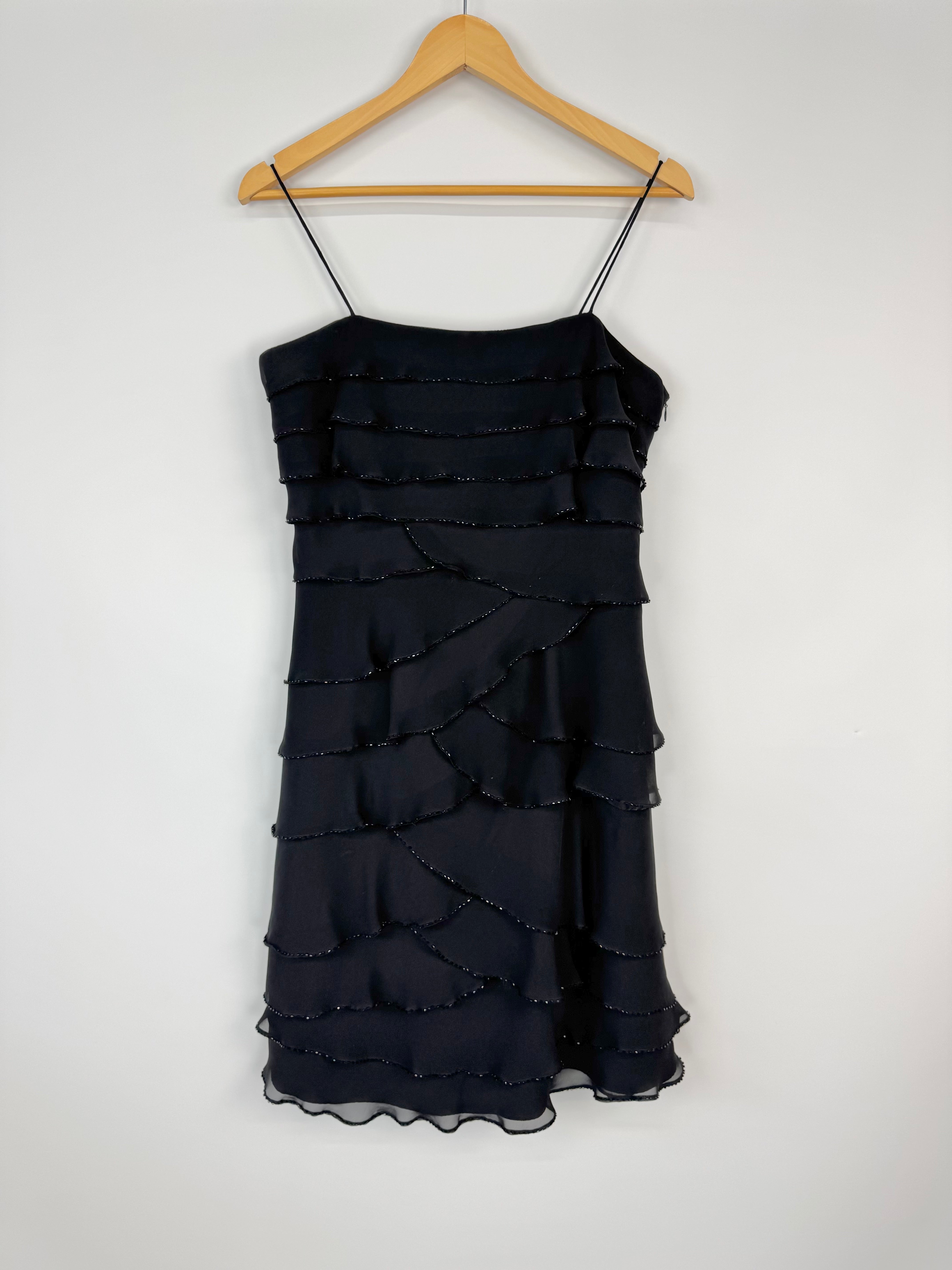 Black ruffled dress on a wooden hanger against a white background