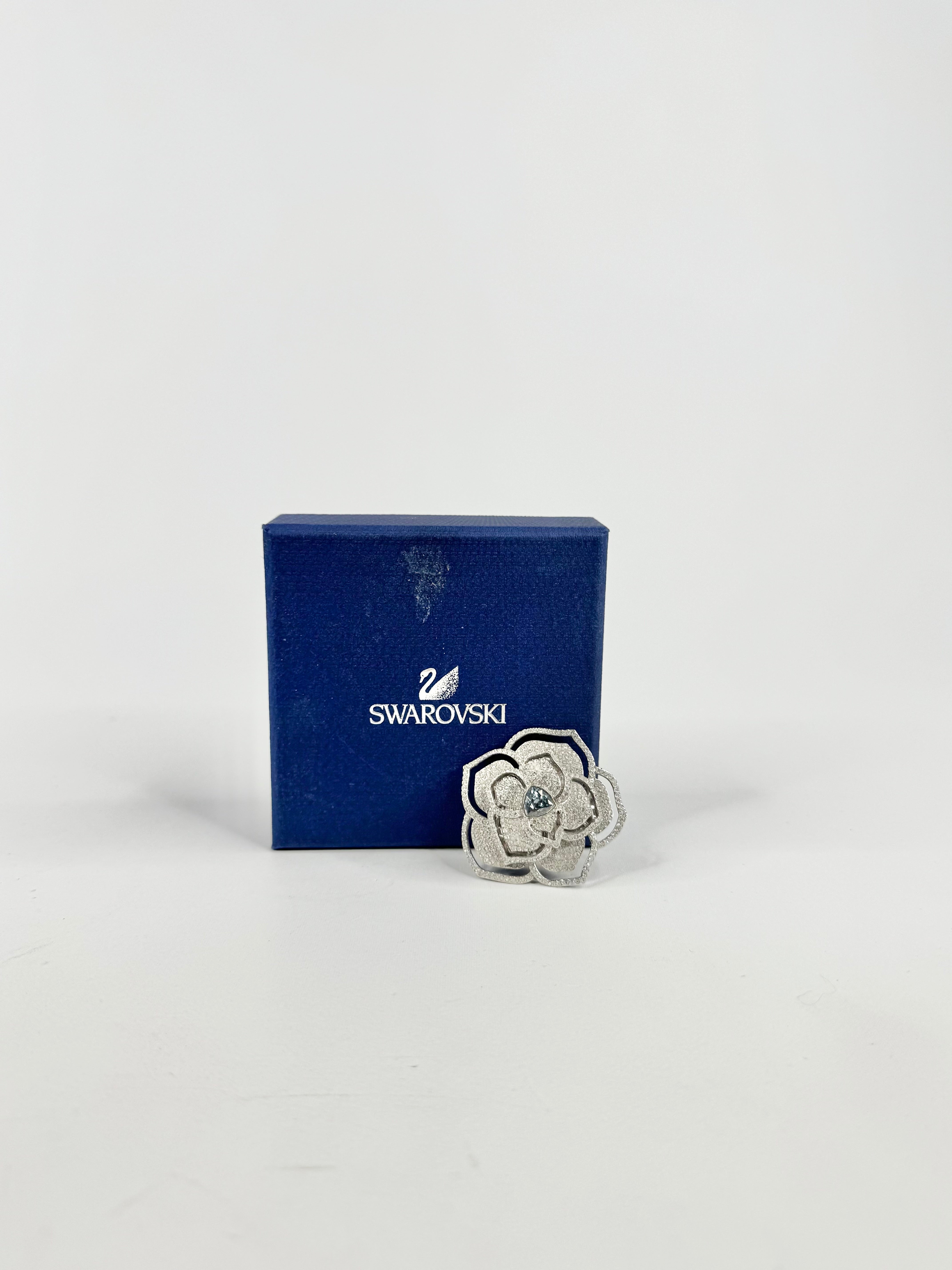 Swarovski brooch in front of a blue Swarovski box on a white background