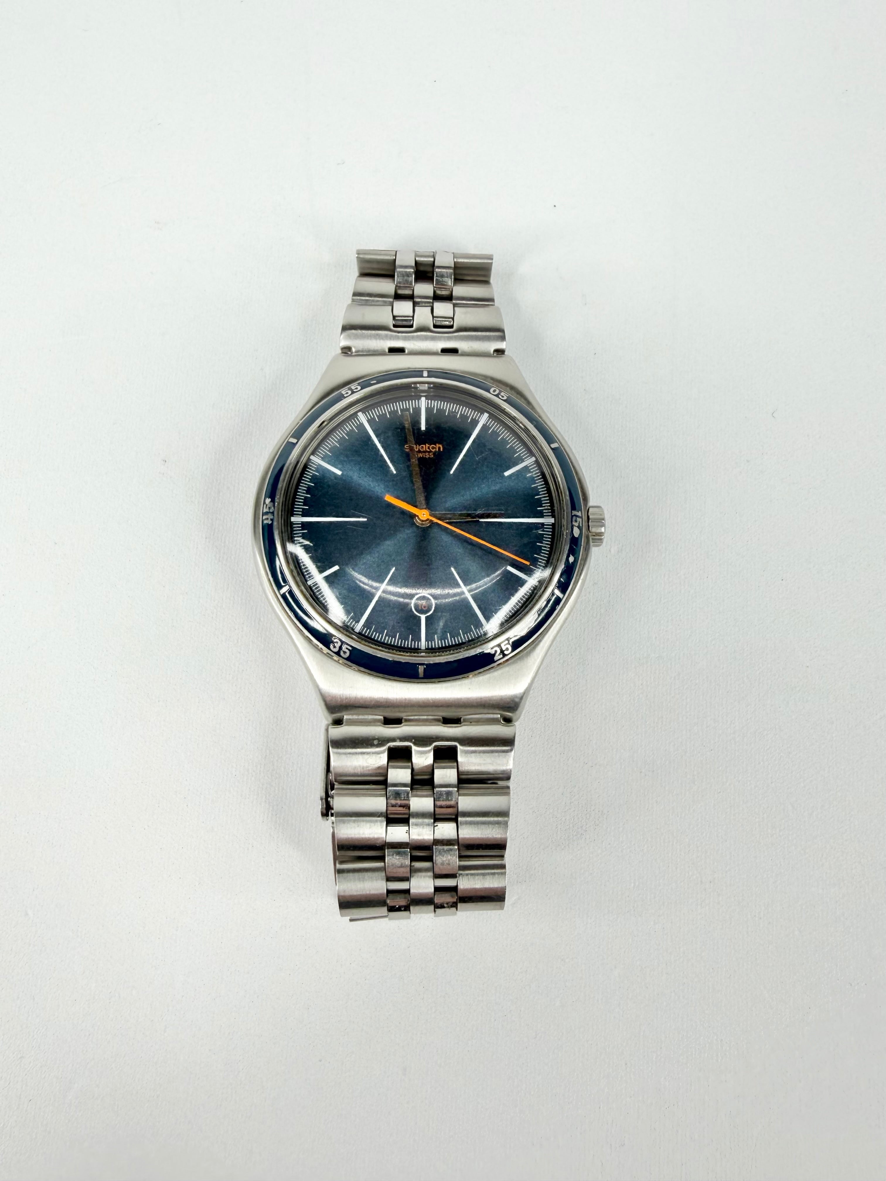 Silver Swatch watch with blue face on a white background