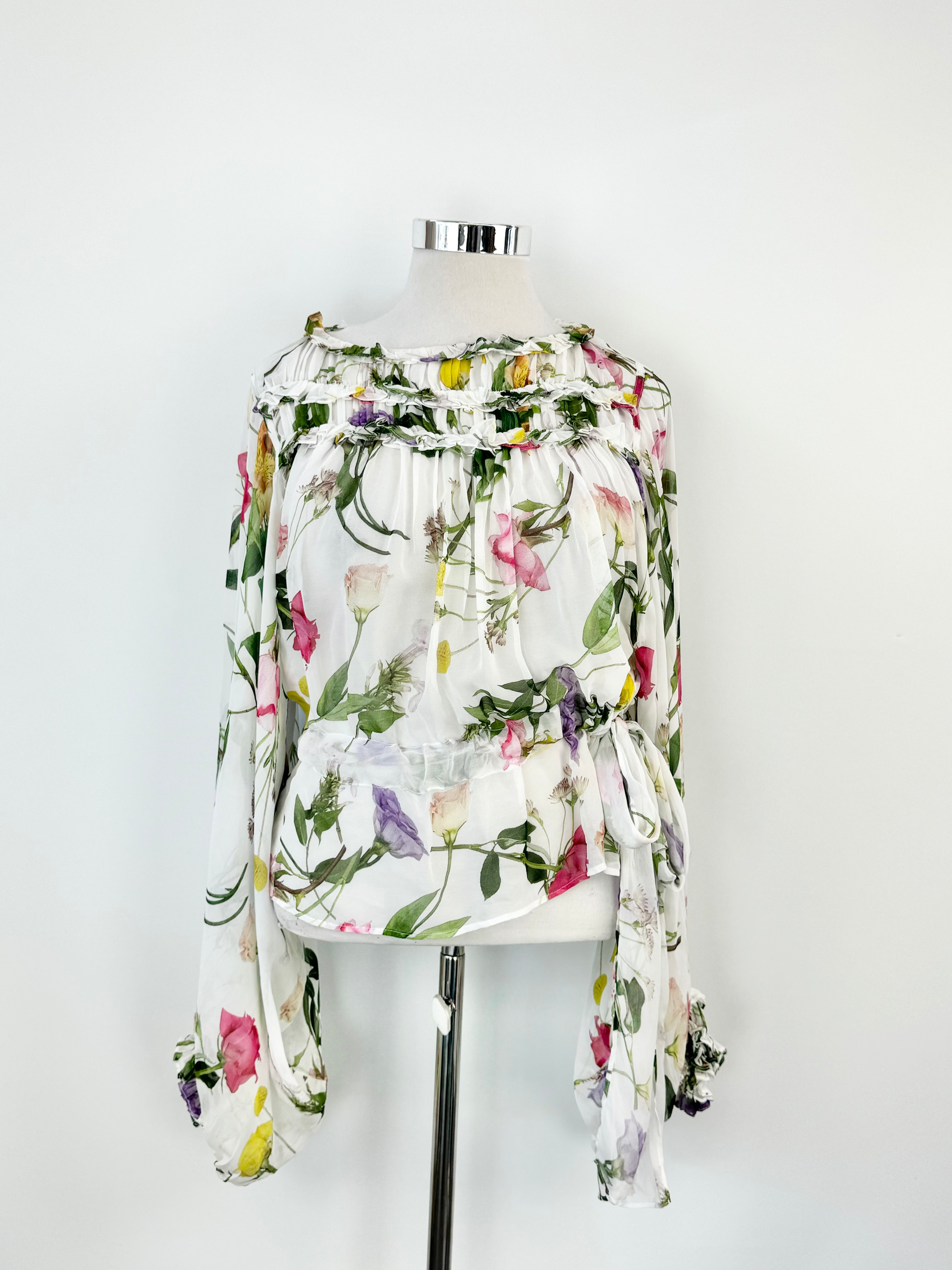 Sheer white floral puff sleeve blouse displayed on a mannequin against a white background.