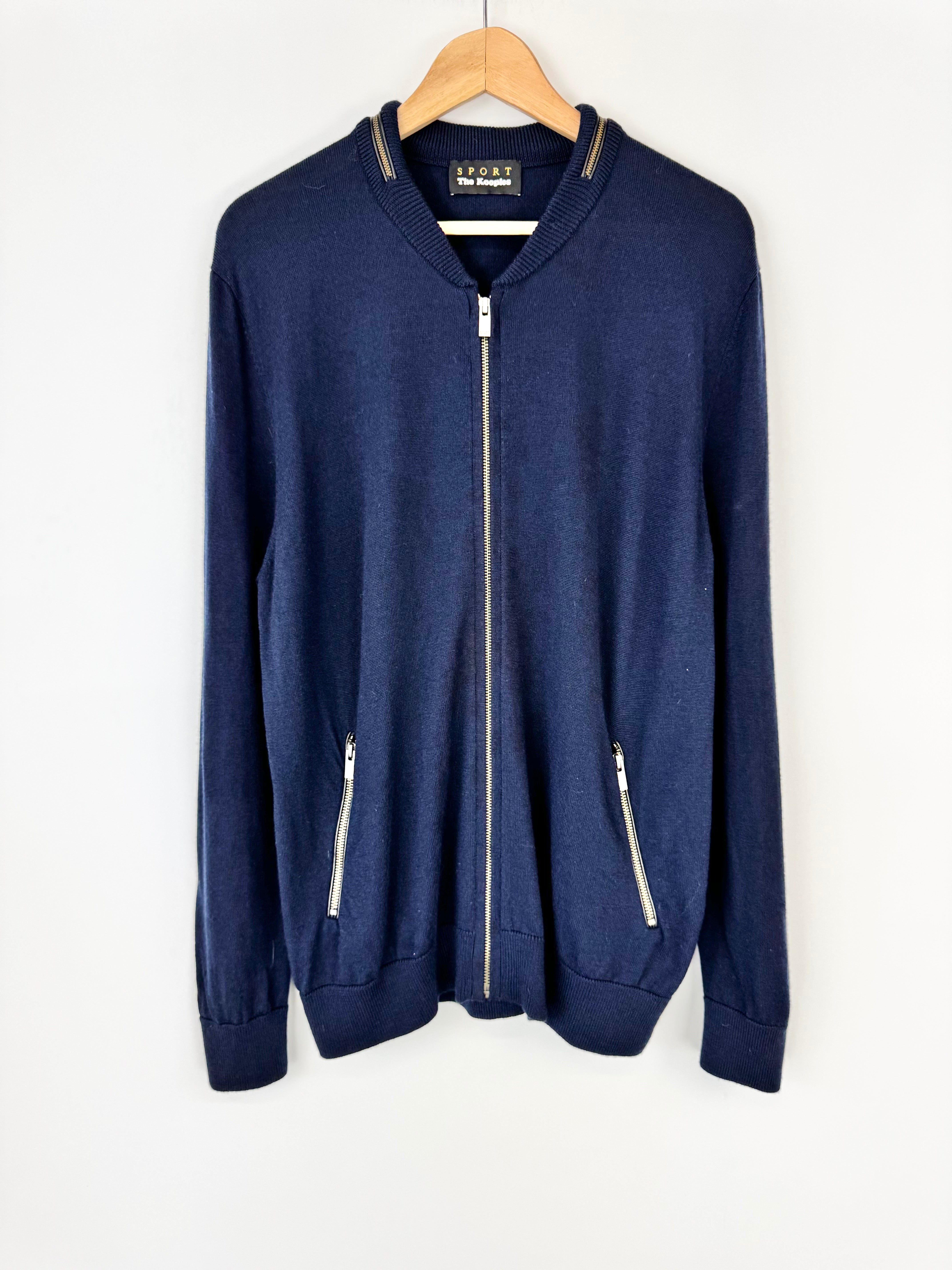 Navy blue zip-up hoodie on a hanger against a white background