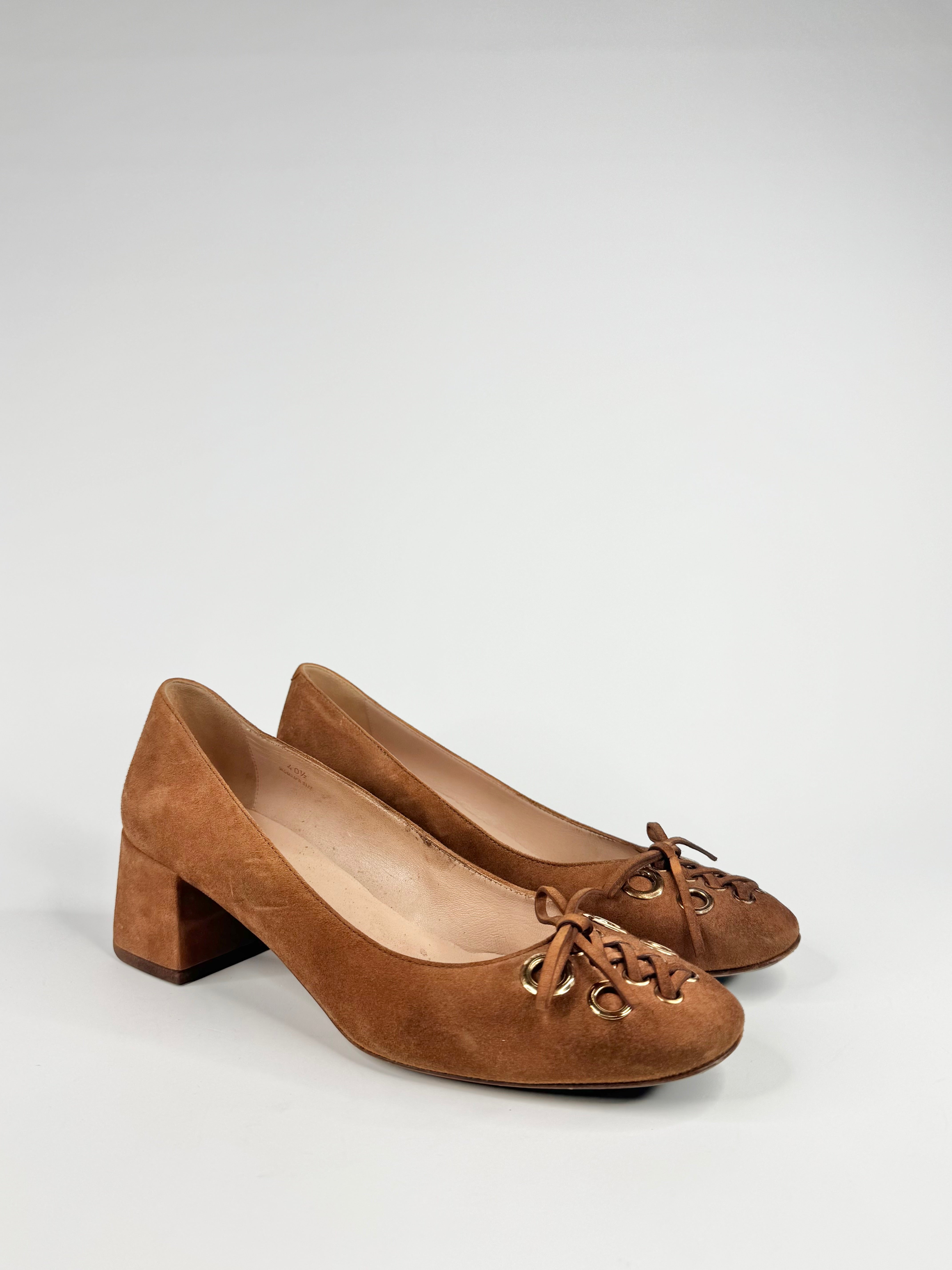 Pair of brown suede shoes with decorative laces on a light gray background