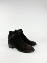 Pair of mahogany suede ankle boots with buckles on a white background