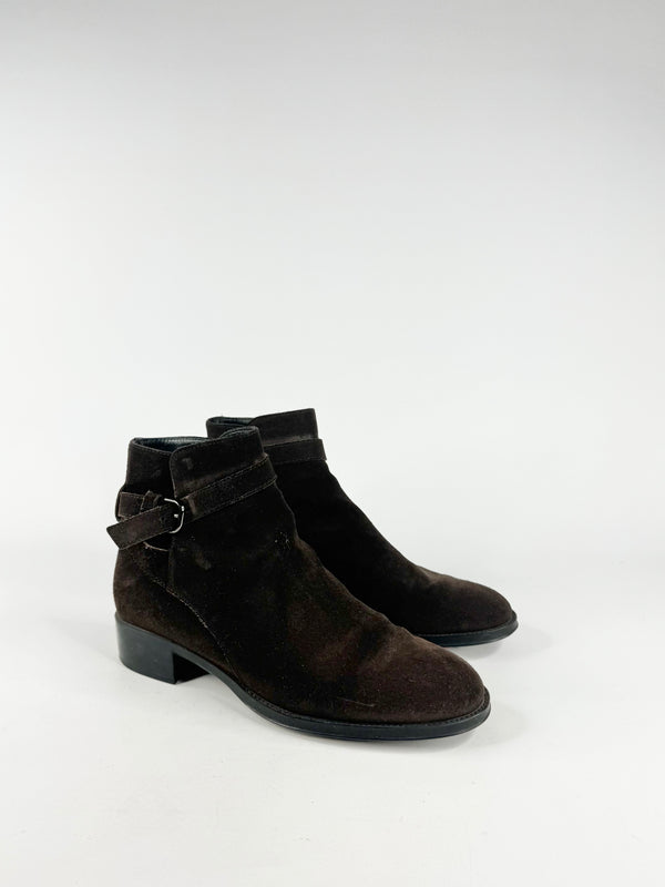 Pair of mahogany suede ankle boots with buckles on a white background