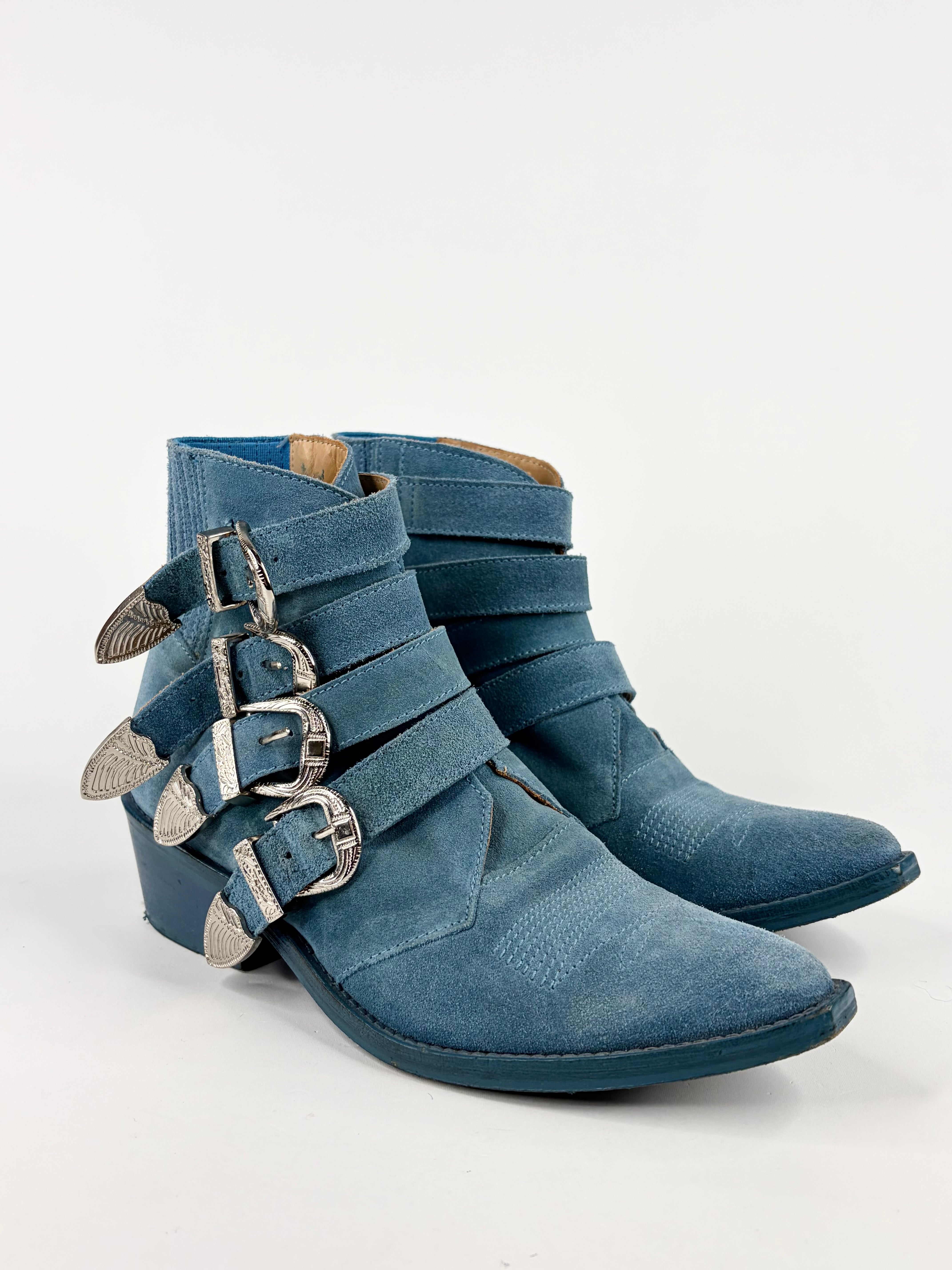 Blue denim ankle boots with silver buckles on a white background
