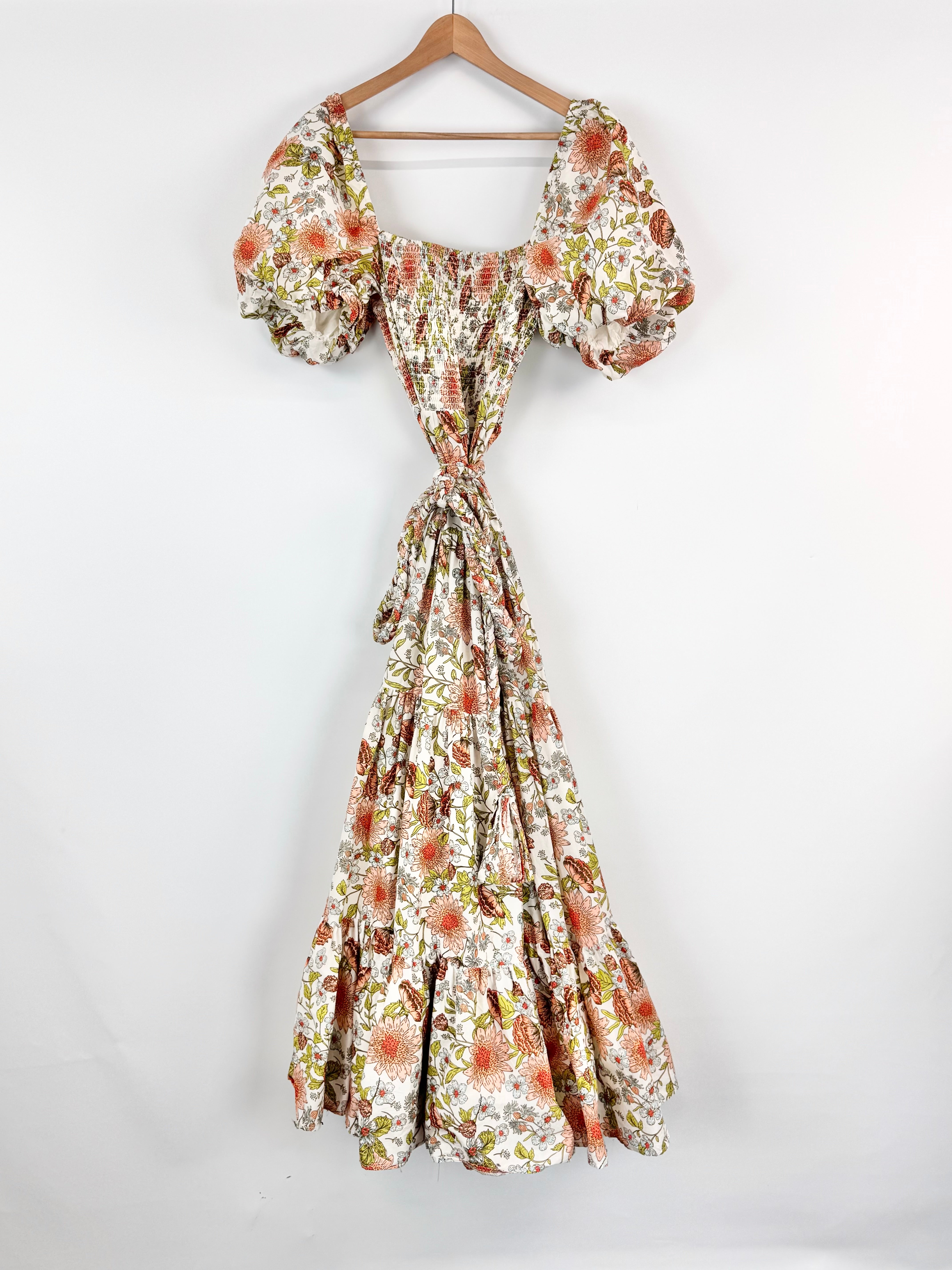 Floral dress with puff sleeves on a hanger against a white background