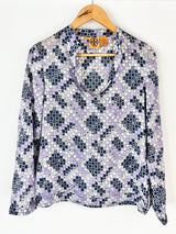 Floral patterned blouse on a hanger against a white background