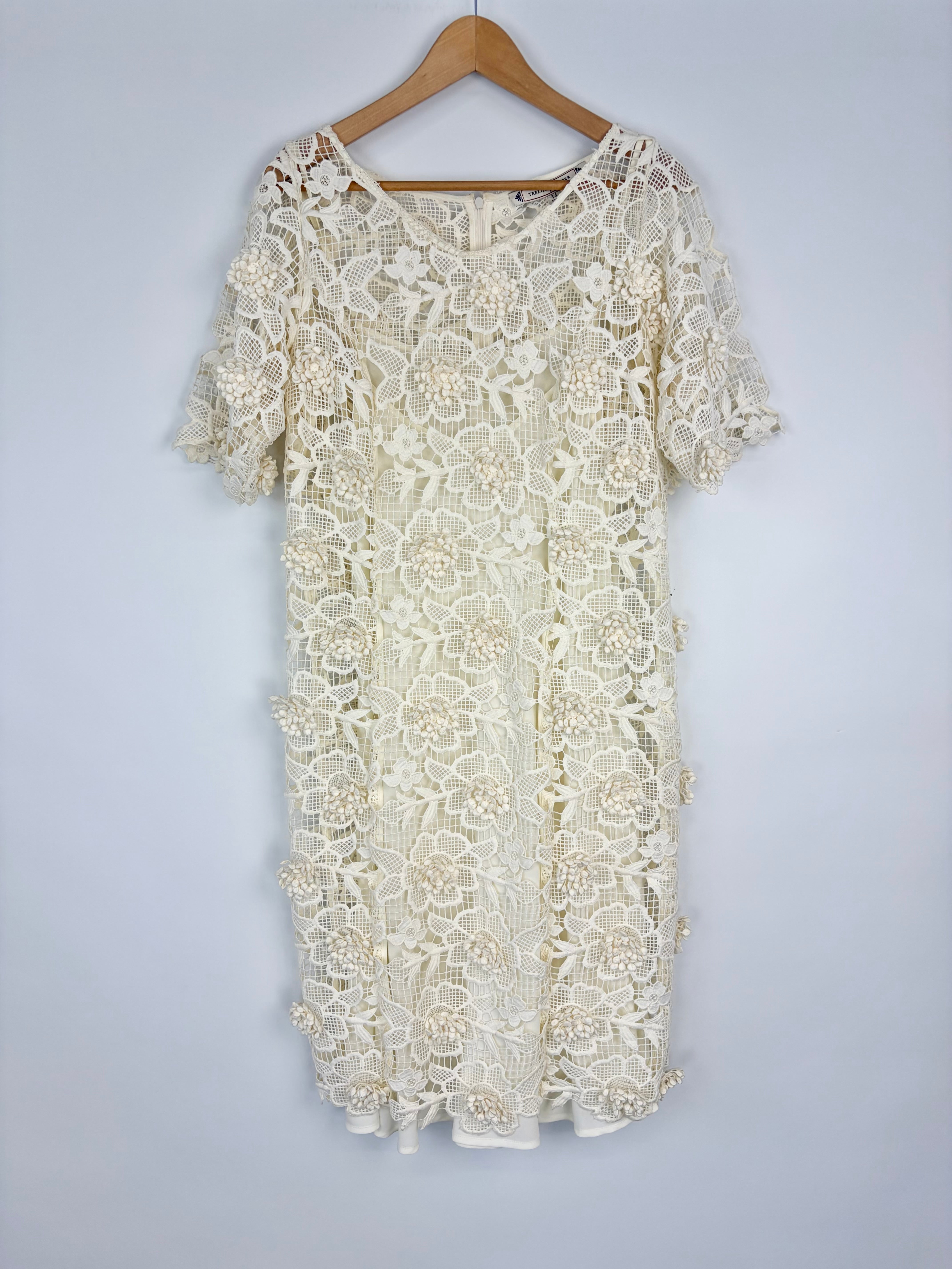 White lace dress on a wooden hanger against a light gray background