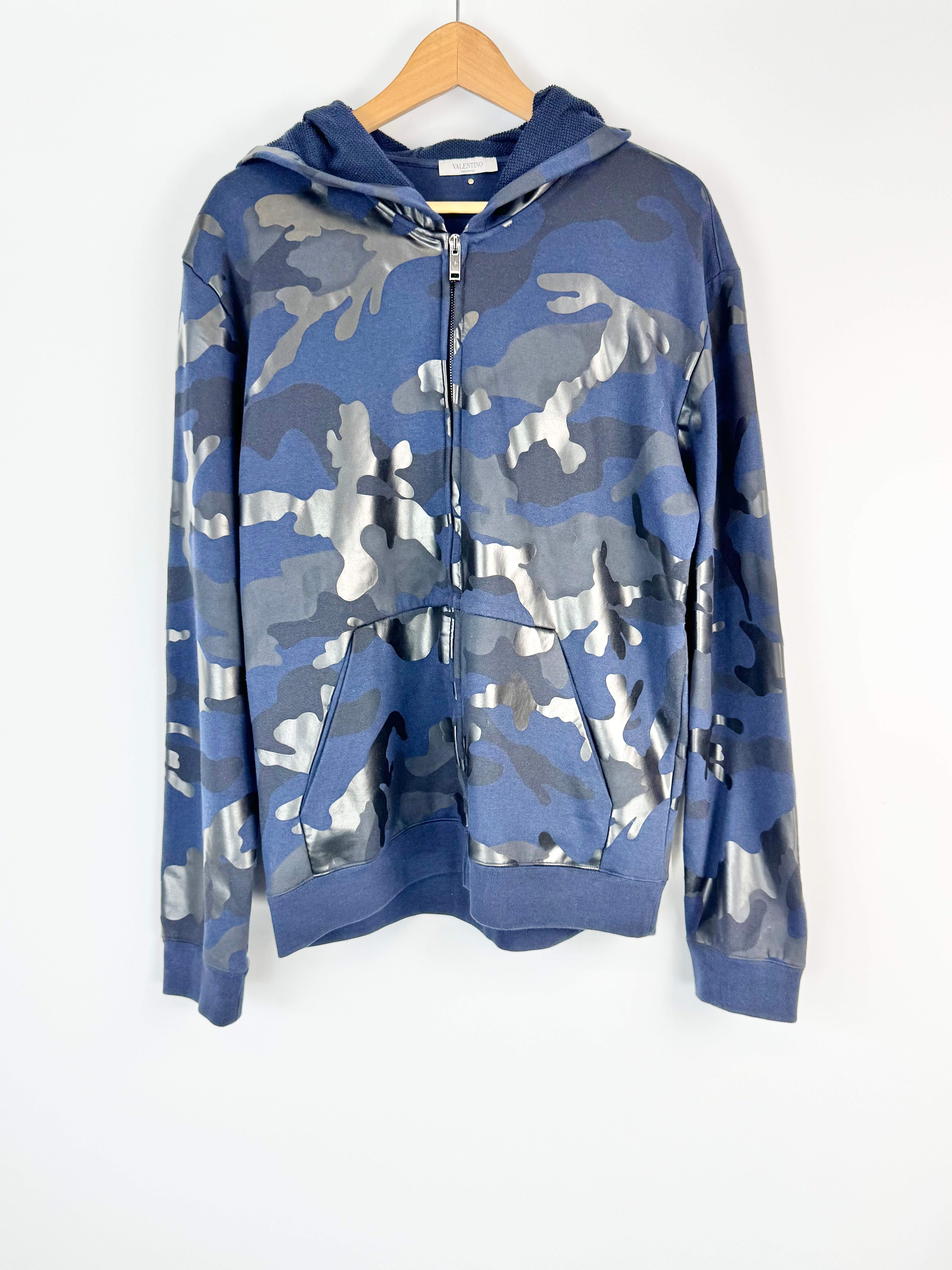 Blue camouflage hoodie on a wooden hanger against a white background