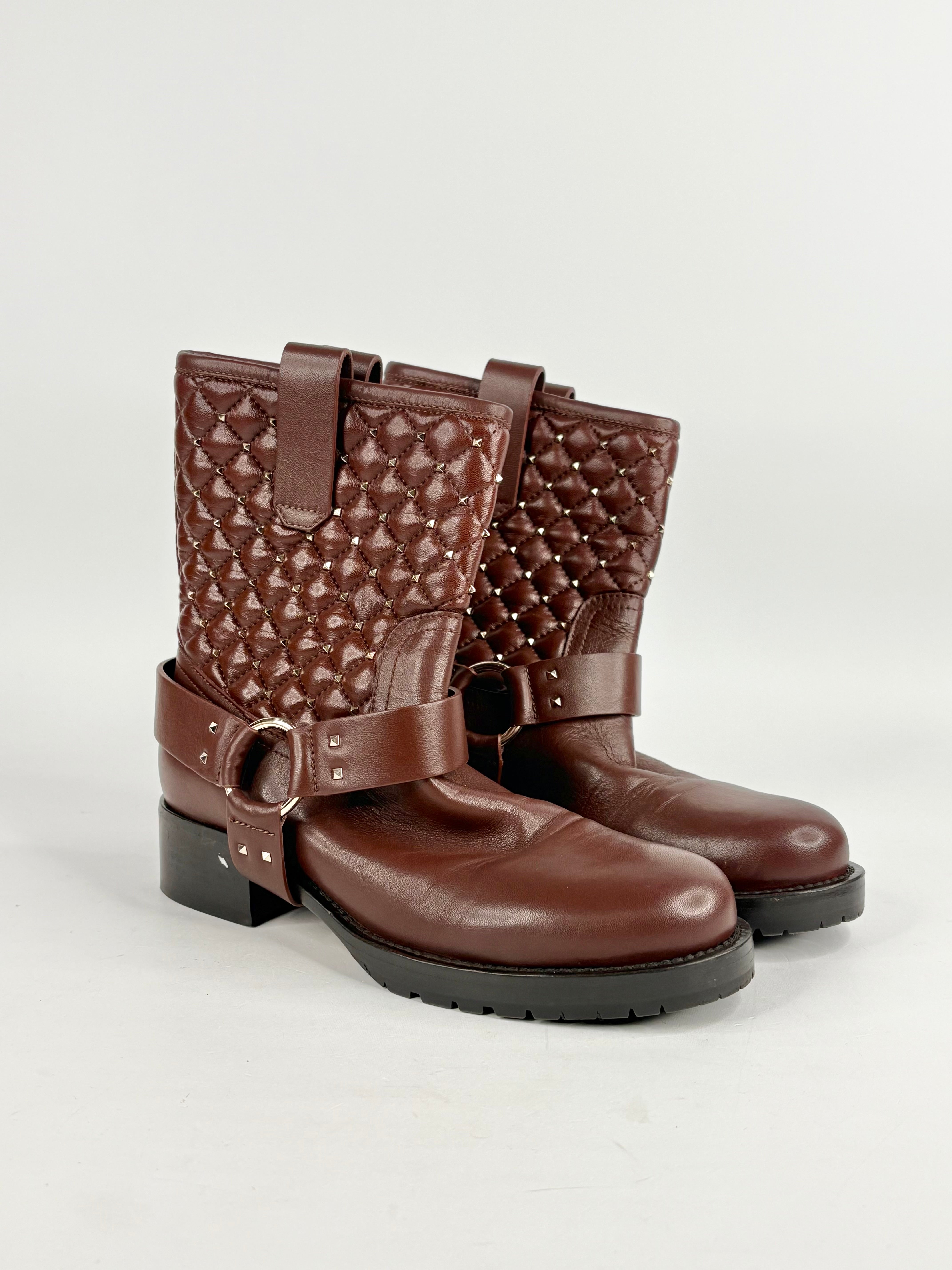 Pair of brown quilted leather boots with buckles on a light gray background