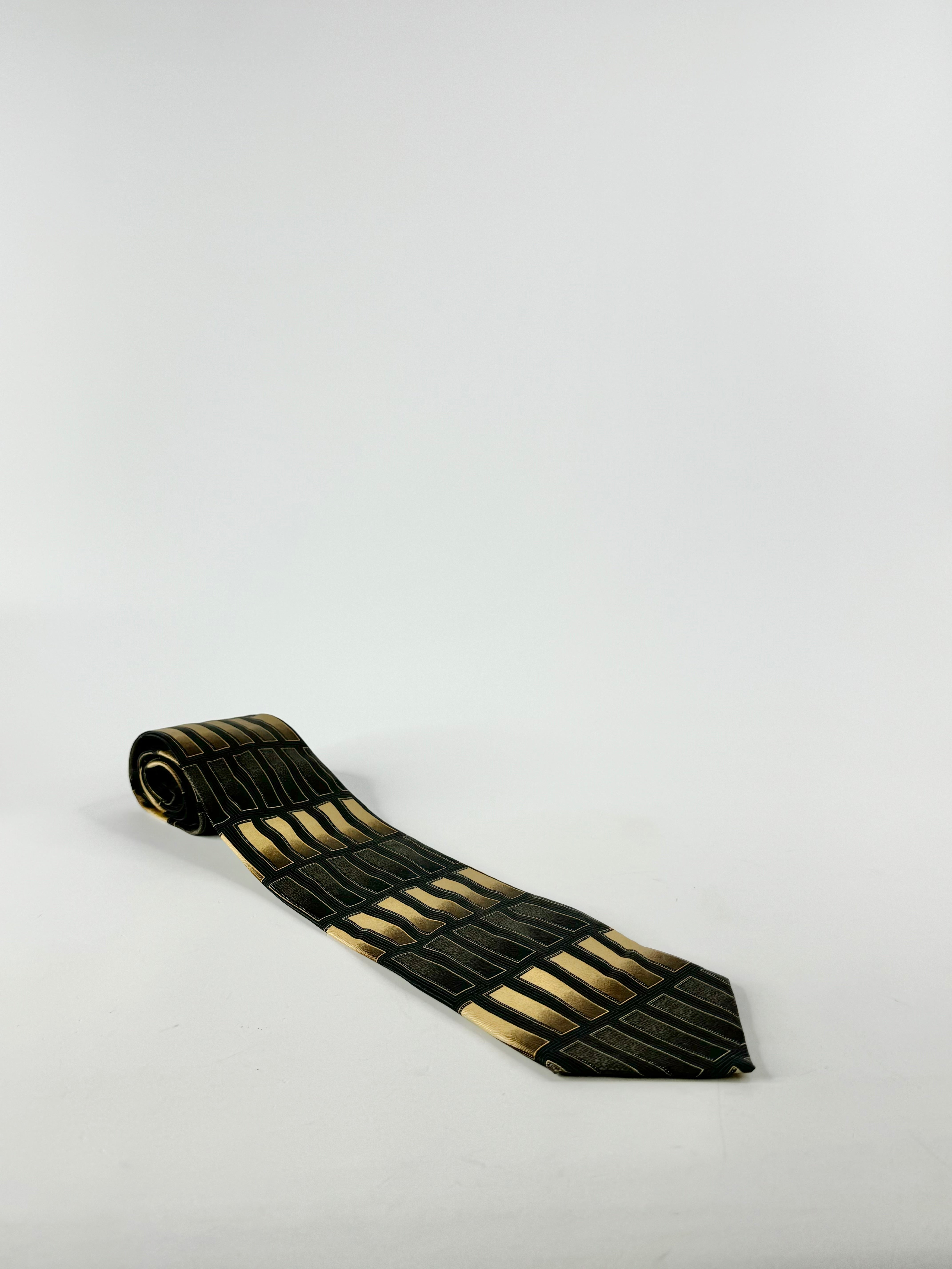 A handmade black, gold, and green silk tie on a white background.