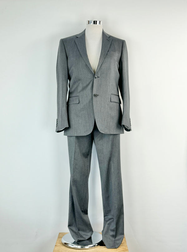 A charcoal grey wool 2 piece suit, consisting of a blazer and slacks, displayed on a mannequin. The mannequin is dressed in a size large suit and shows some signs of wear.