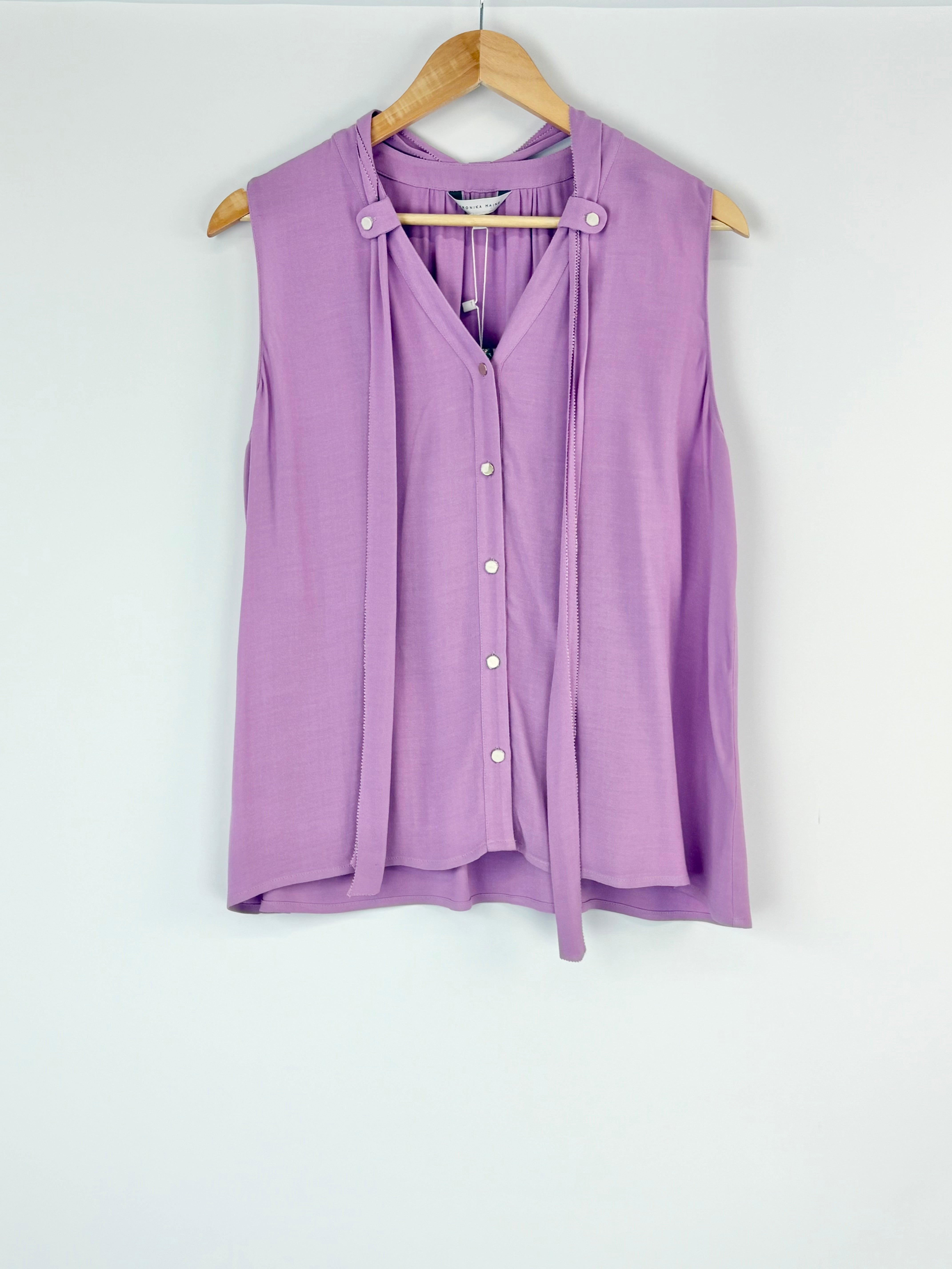 Purple sleeveless blouse on a wooden hanger against a white background