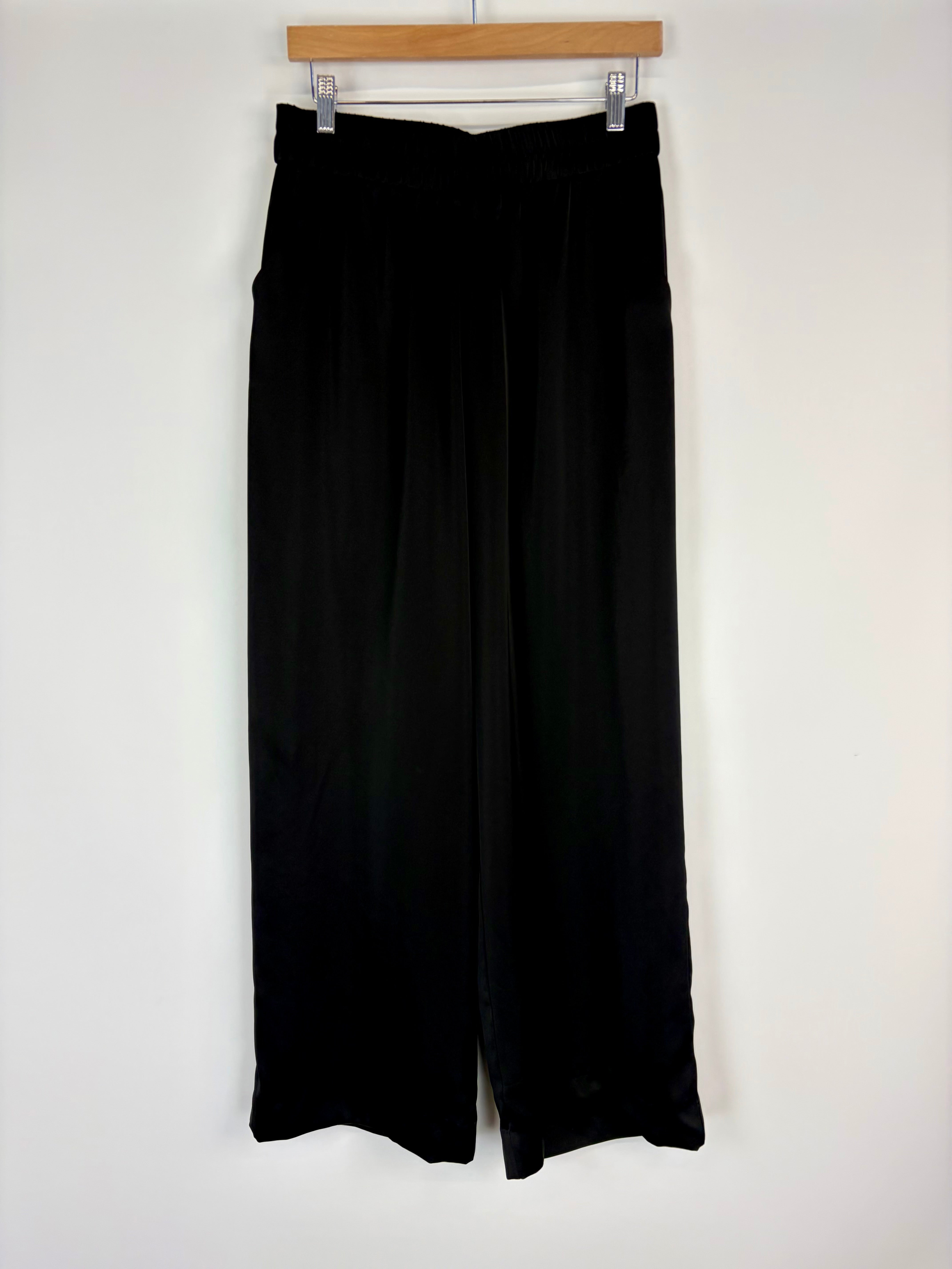 Black skirt hanging on a wooden hanger against a white wall
