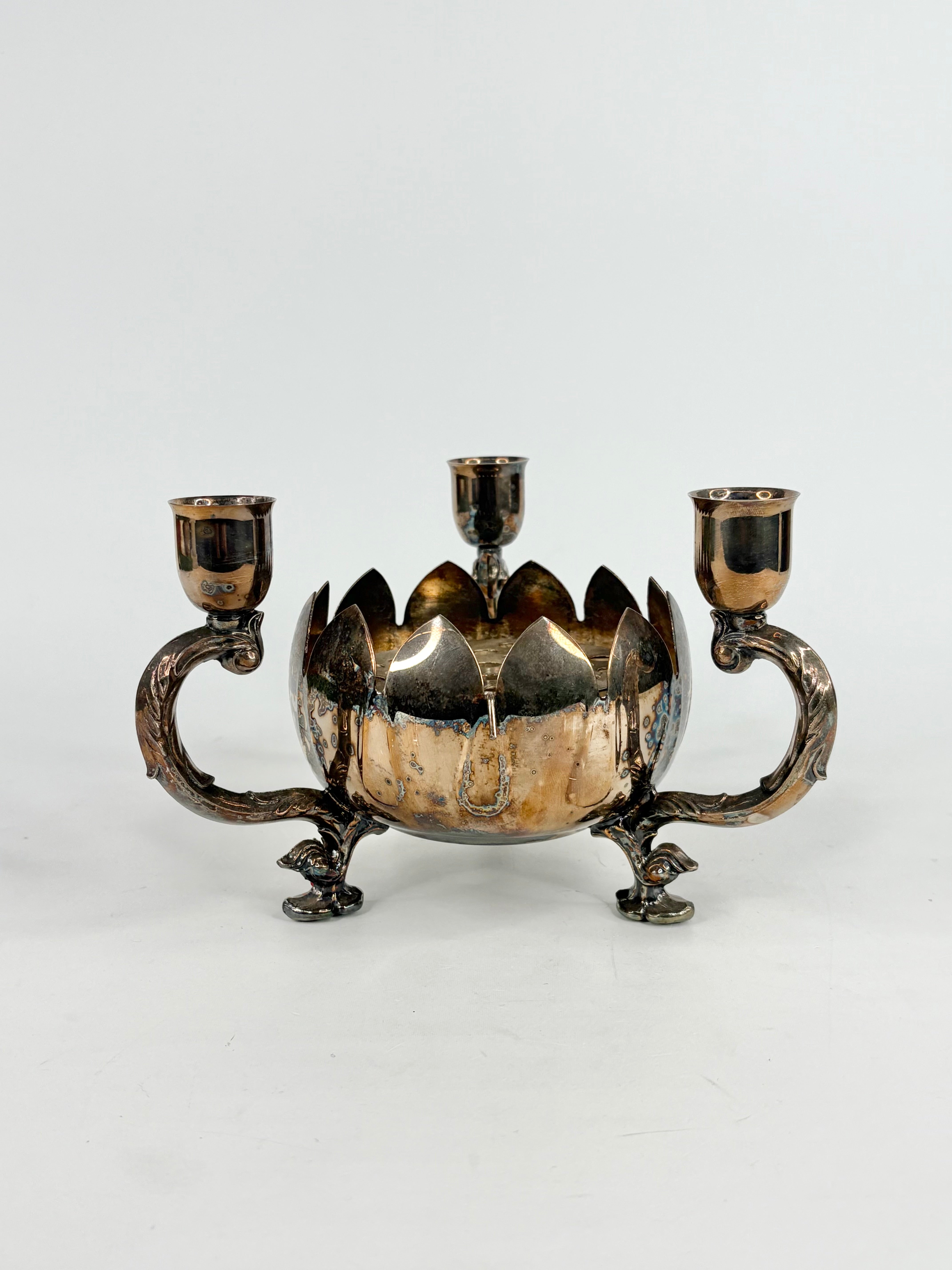 Decorative silver candle holder with three candle holders on a white background