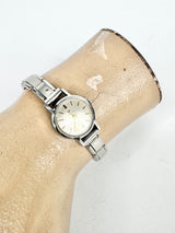 Silver watch on a beige arm with a white background