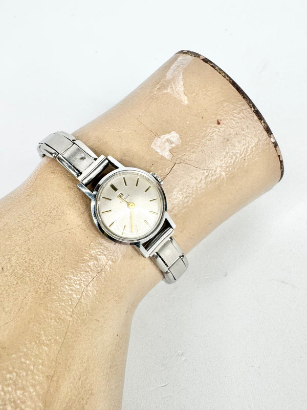 Silver watch on a beige arm with a white background