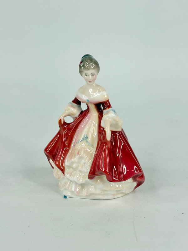 Porcelain figurine of a woman in a red dress on a light gray background