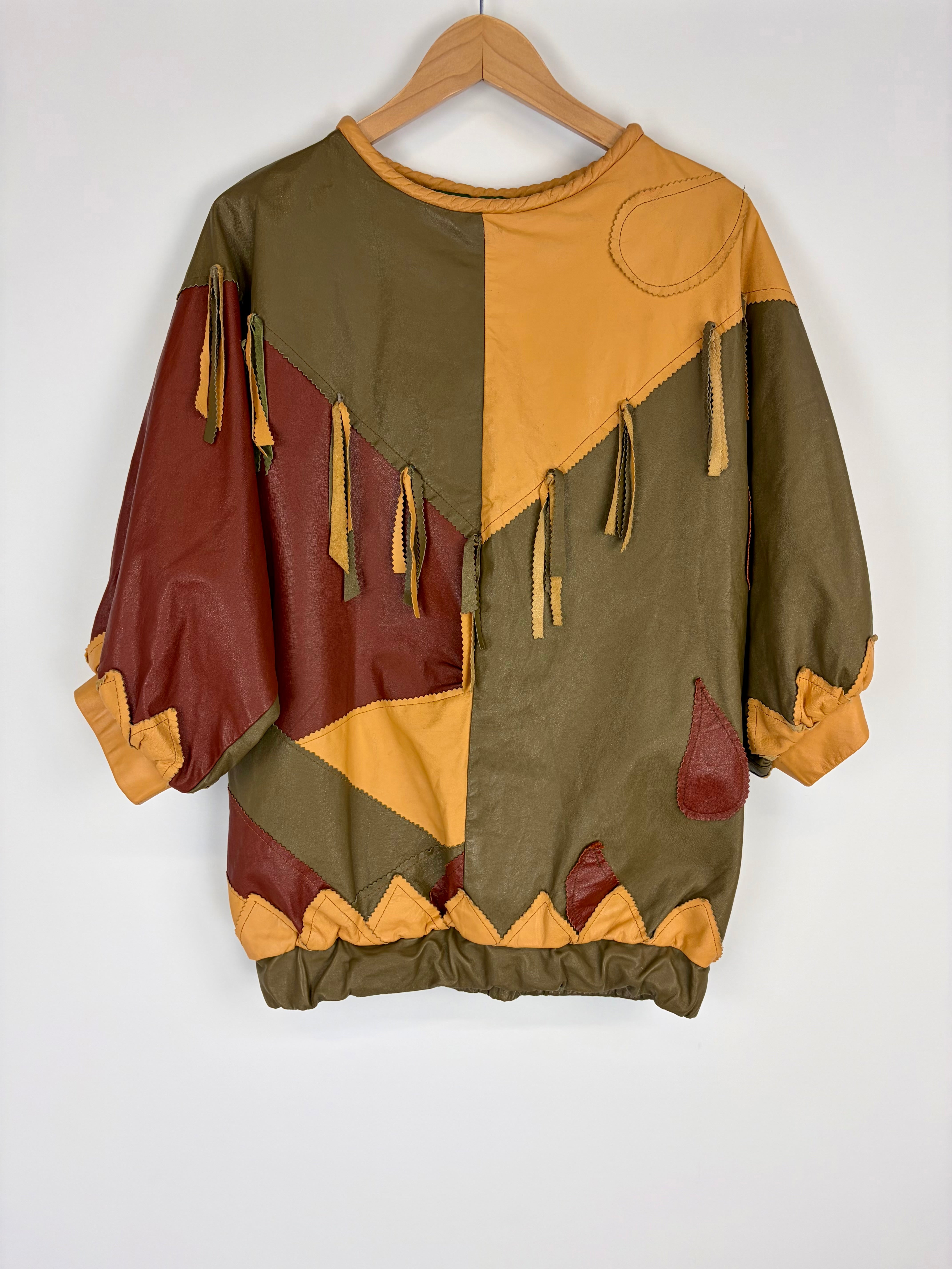 Color-blocked sweater with brown, green, and beige sections on a hanger against a white background
