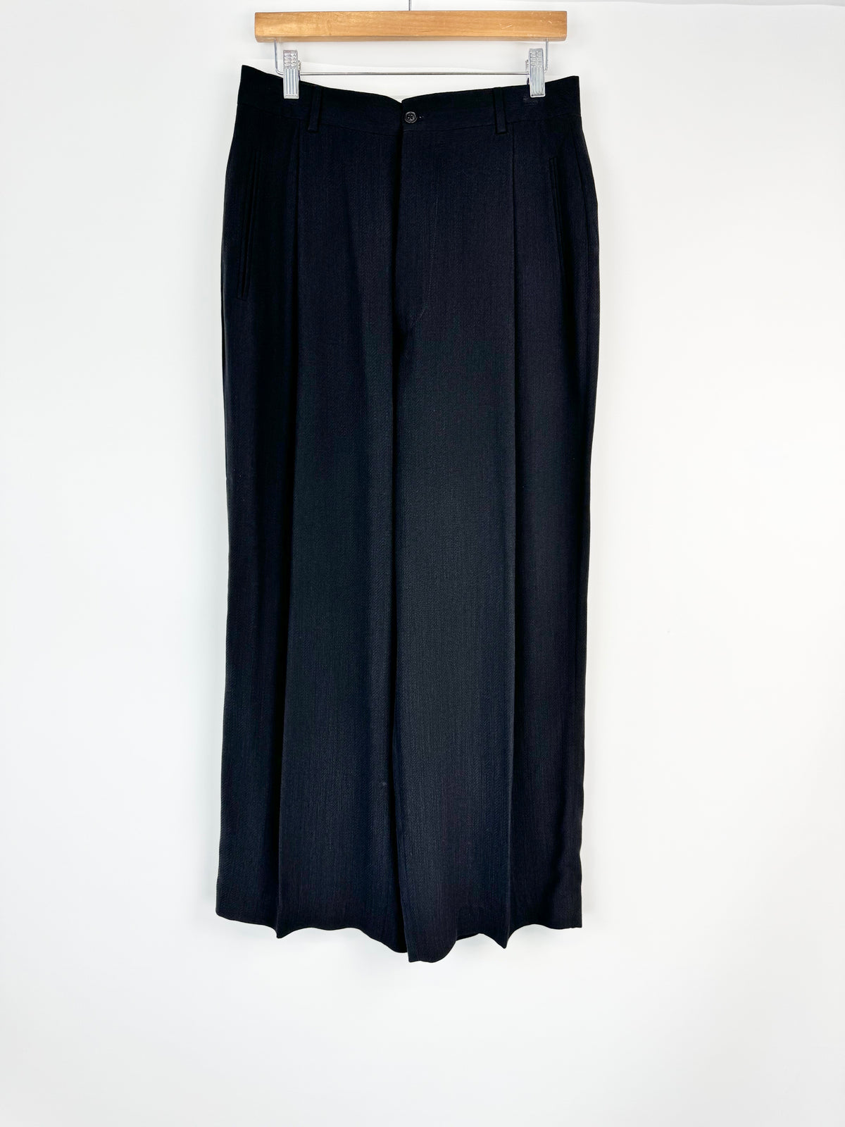 Black skirt hanging on a wooden hanger against a white background