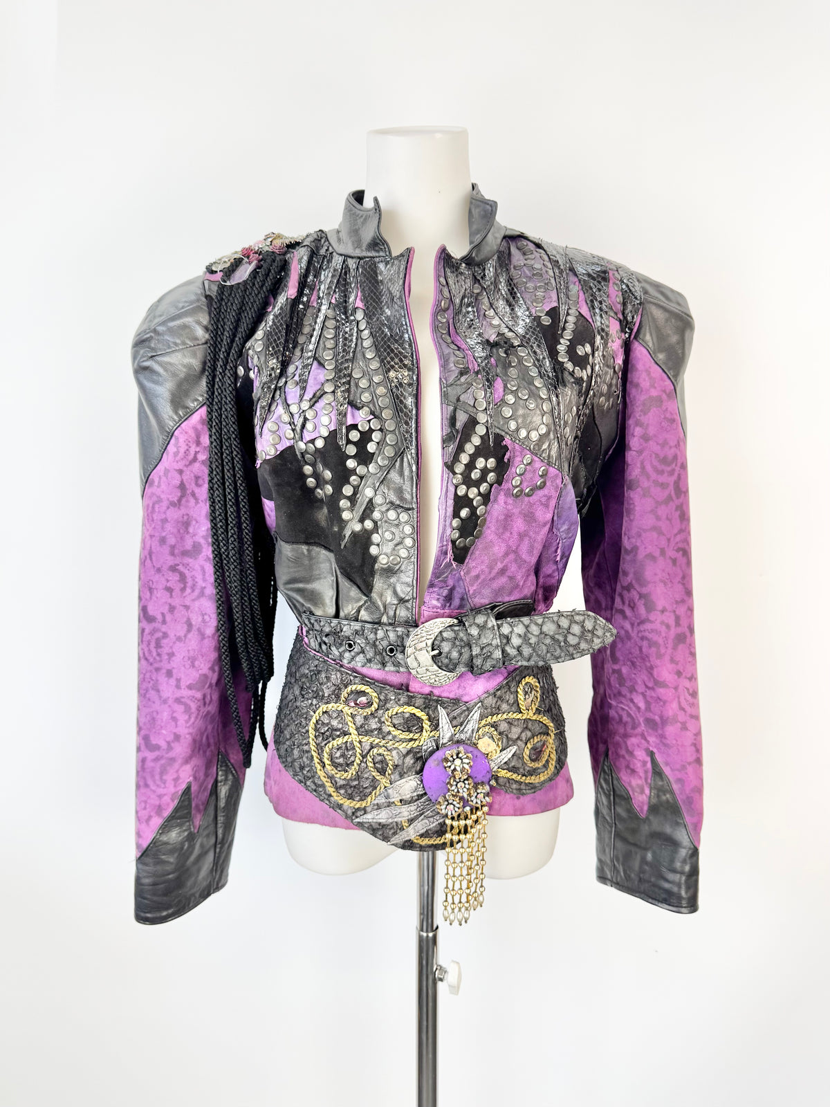 Mannequin wearing a purple and gray patterned top with decorative elements on a white background